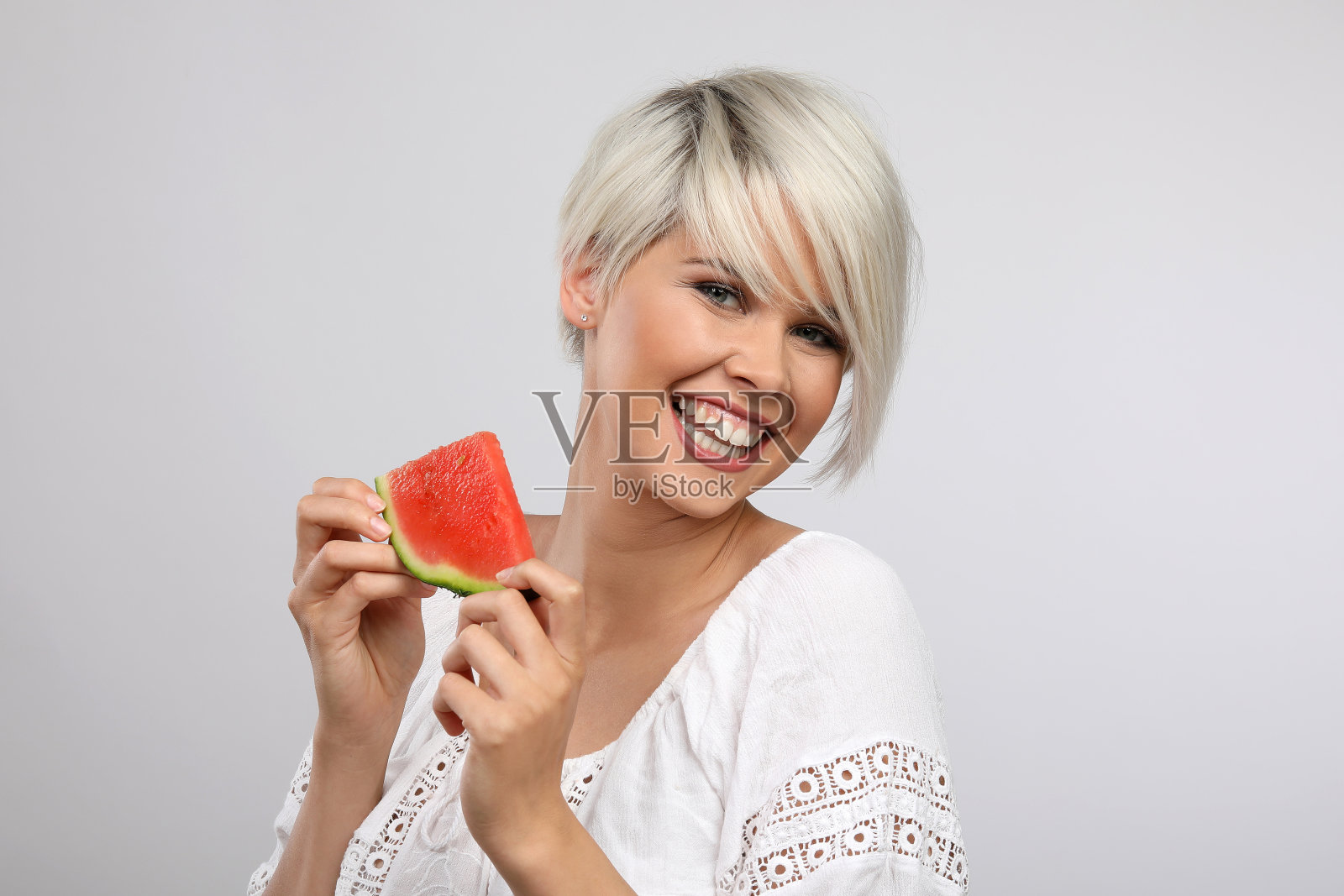 年轻漂亮的银发女子在演播室里吃着西瓜照片摄影图片