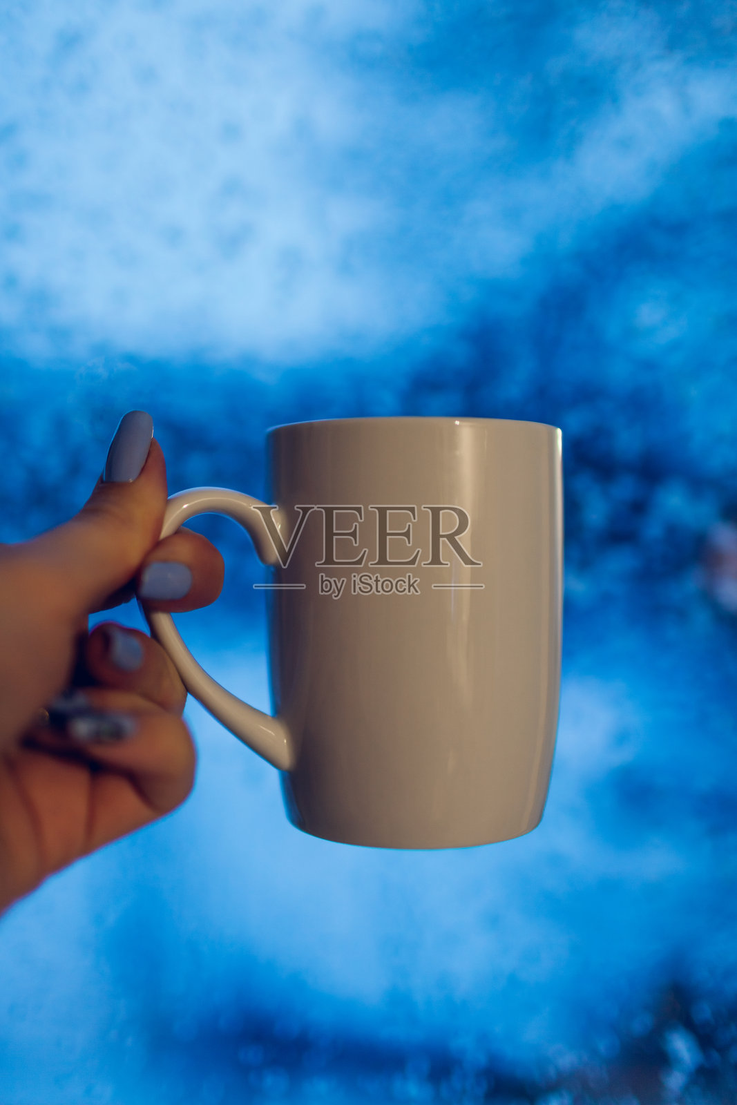 冬季饮料。晚上在下雪的窗户前喝杯茶或咖啡。女人在家里喝饮料感觉很舒适照片摄影图片