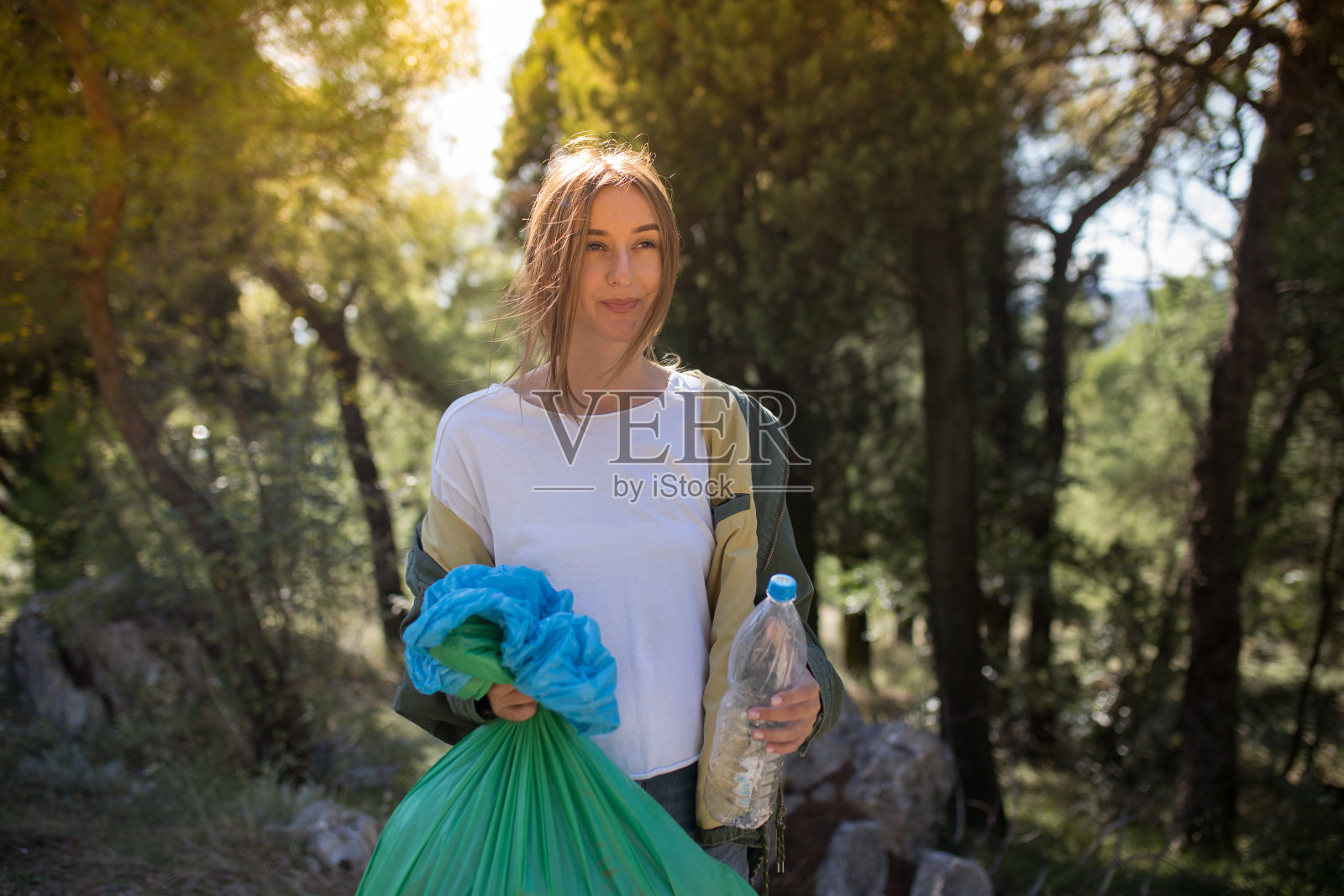 年轻的妇女志愿者清理森林中的塑料垃圾照片摄影图片