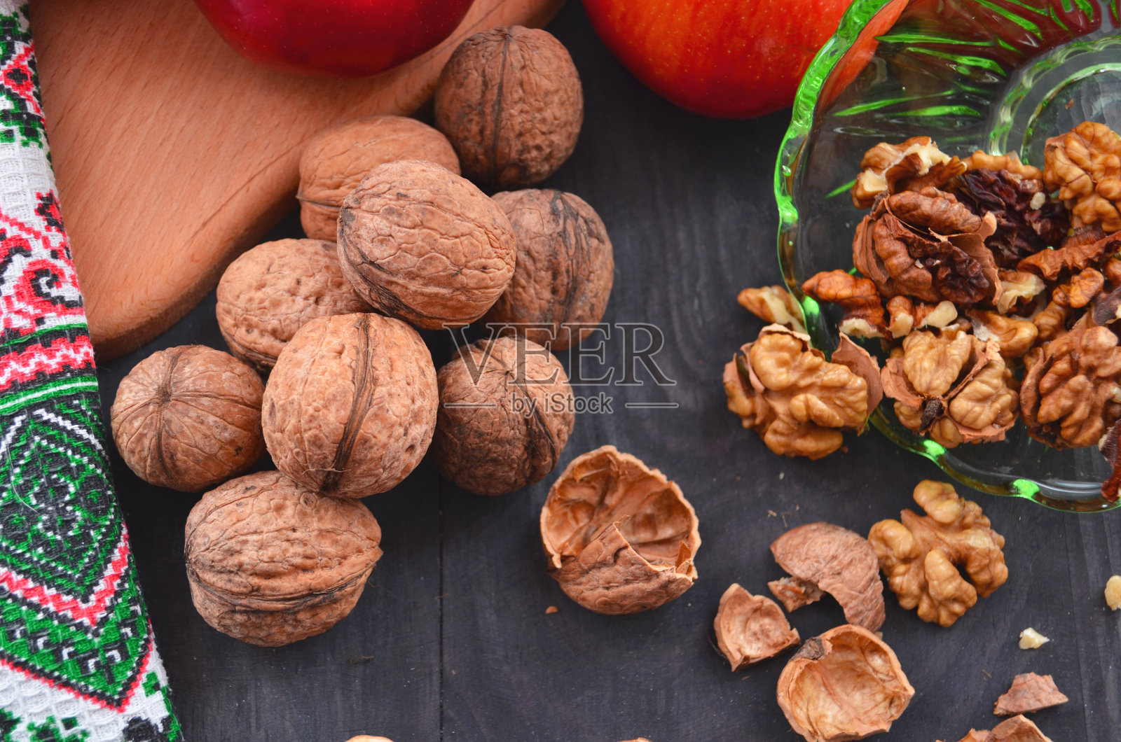 成熟的苹果和核桃摆在桌上。剥皮坚果,并把它们放在架子上。照片摄影图片