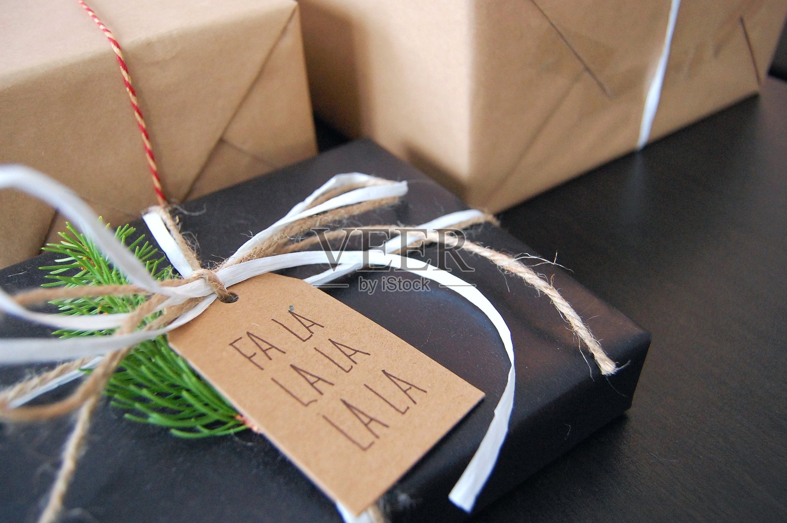 圣诞礼物包装在黑色装饰纸与礼物标签和云杉树枝照片摄影图片