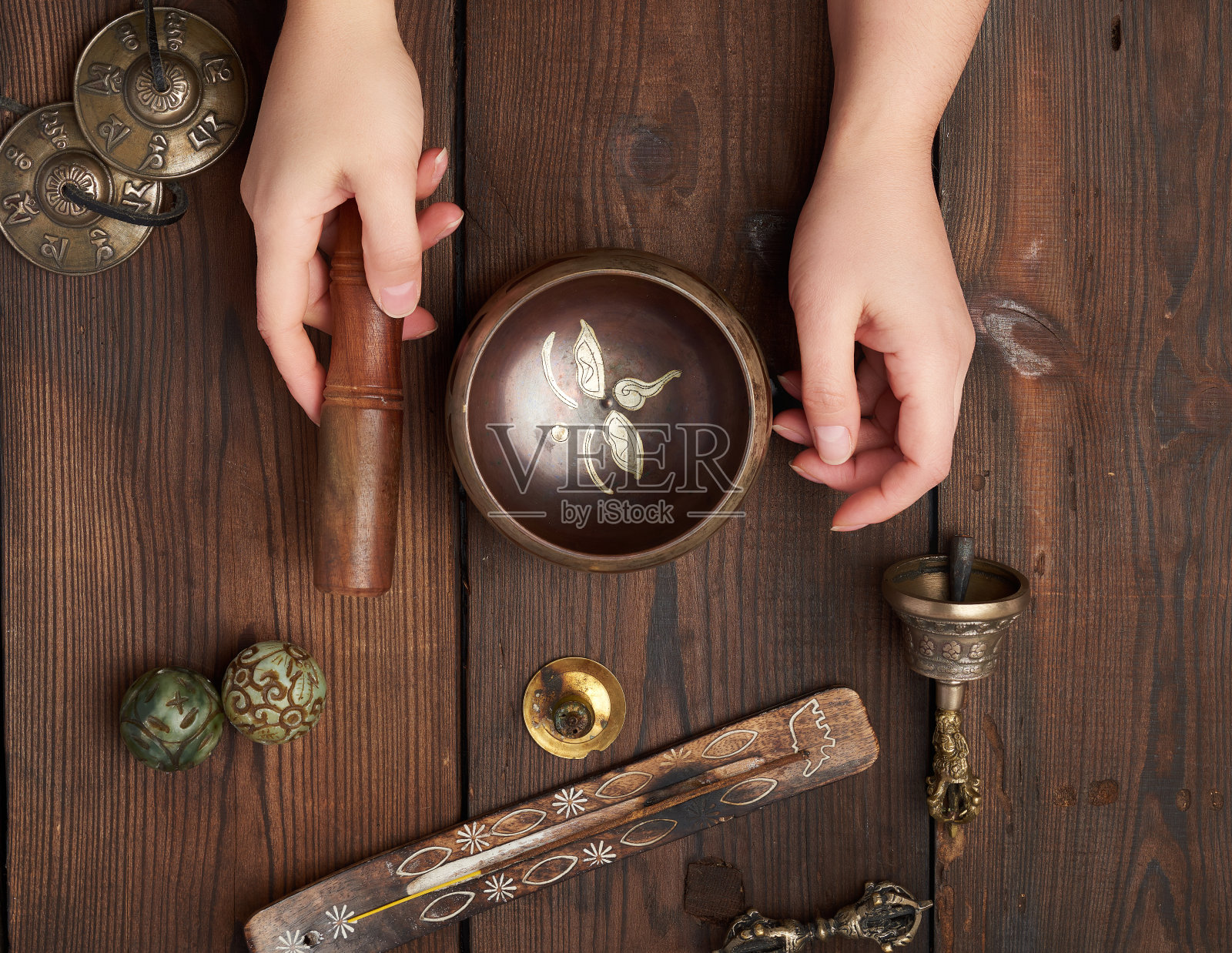 女人手持铜制西藏颂钵和木棍照片摄影图片