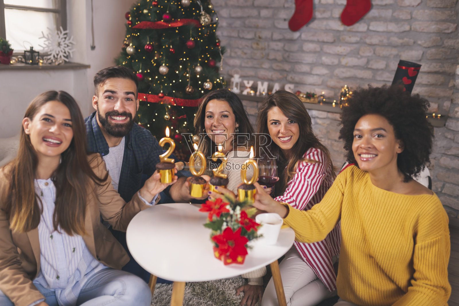 朋友们拿着纸杯蛋糕,上面点着数字2020的蜡烛照片摄影图片