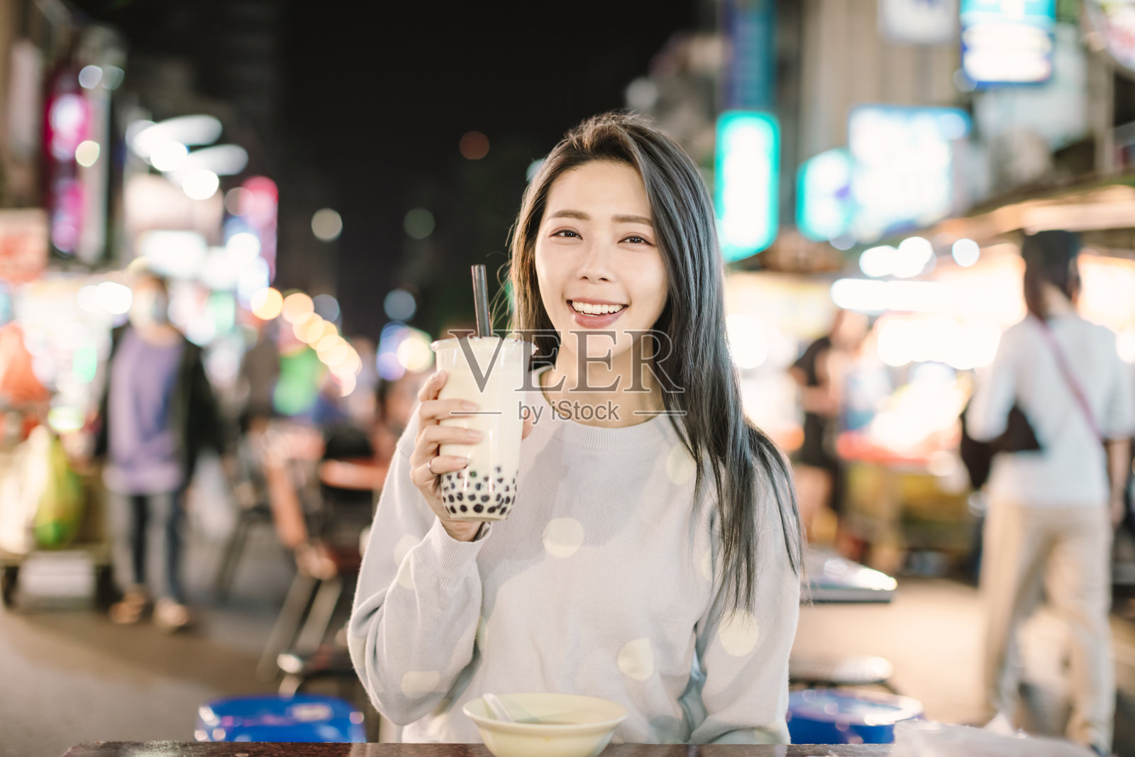 在夜市品尝珍珠奶茶和街头小吃的亚洲女性照片摄影图片