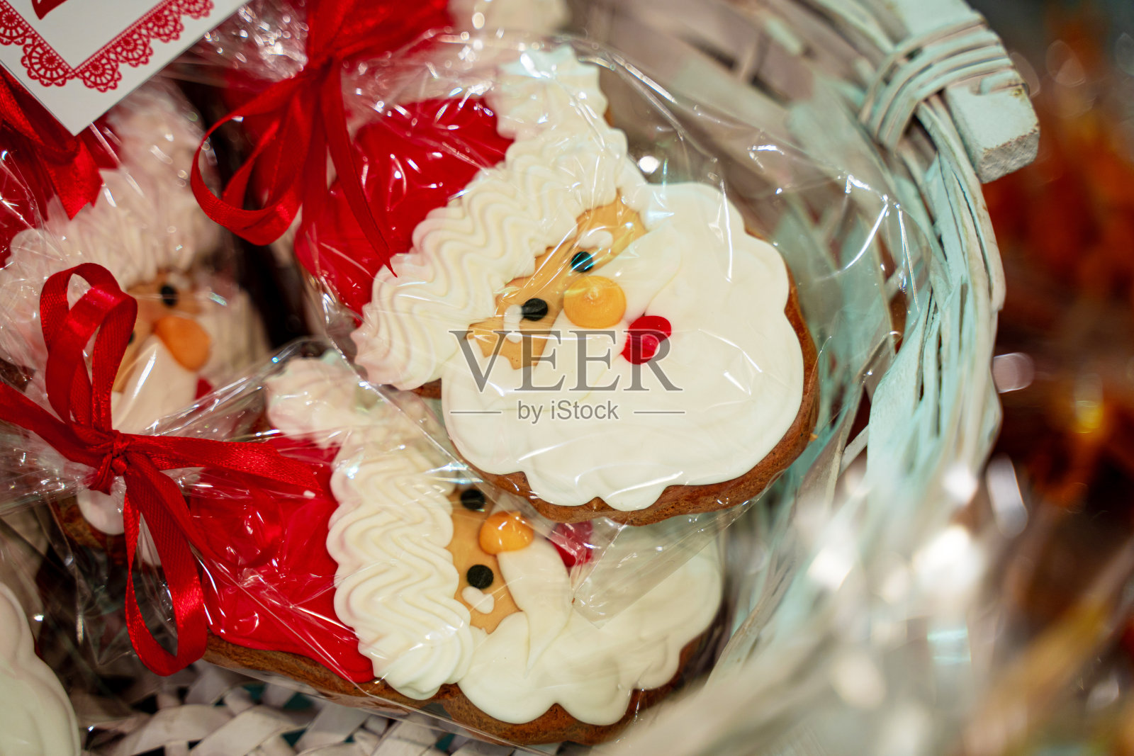 圣诞节手工制作的姜饼饼干放在木篮子里,圣诞老人头形的蛋糕用红色的蝴蝶结包装照片摄影图片