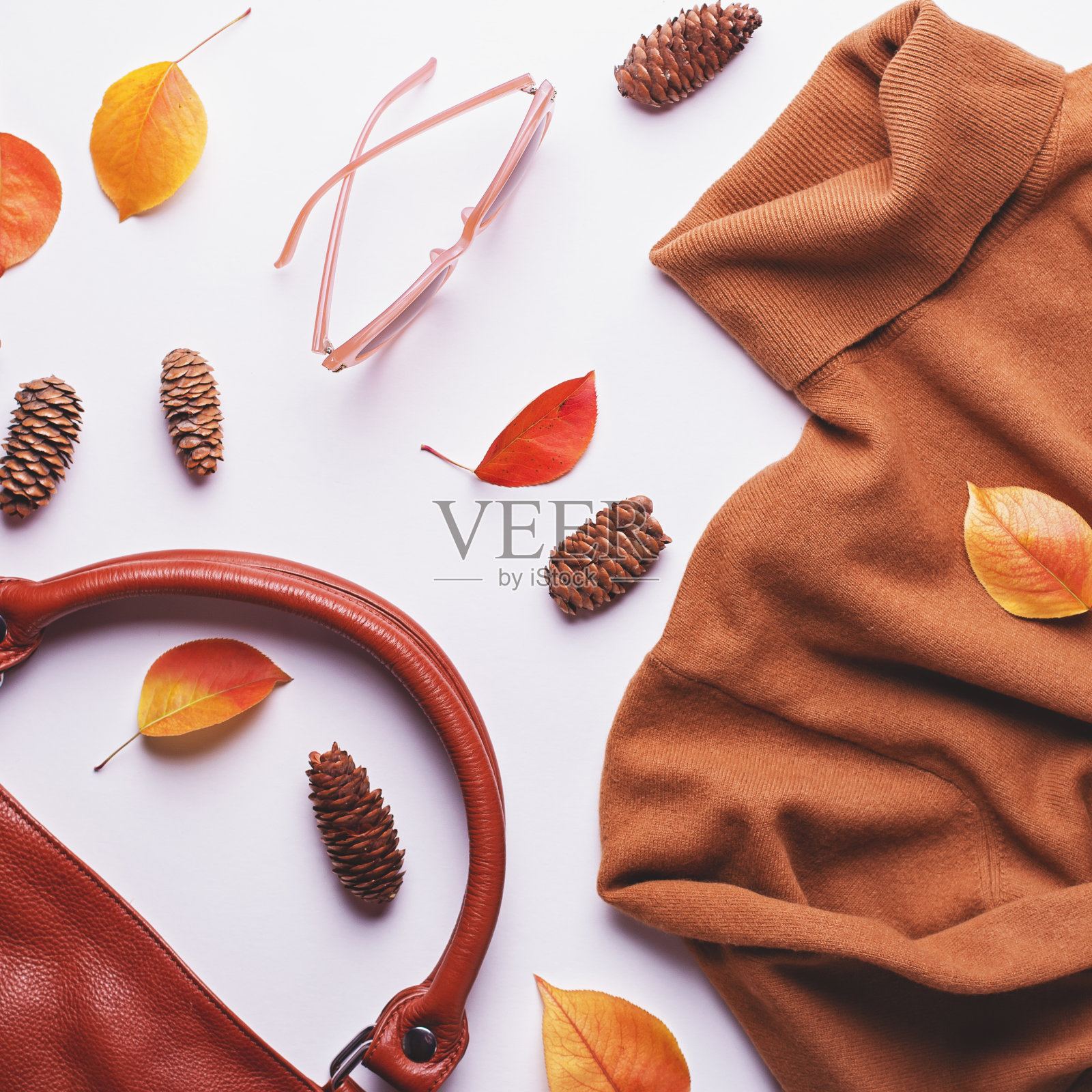 女士棕色毛衣或连衣裙搭配皮包、太阳镜、珠宝、时尚配饰和秋叶。秋季时尚背景。女人秋衣配饰平铺,复制空间照片摄影图片