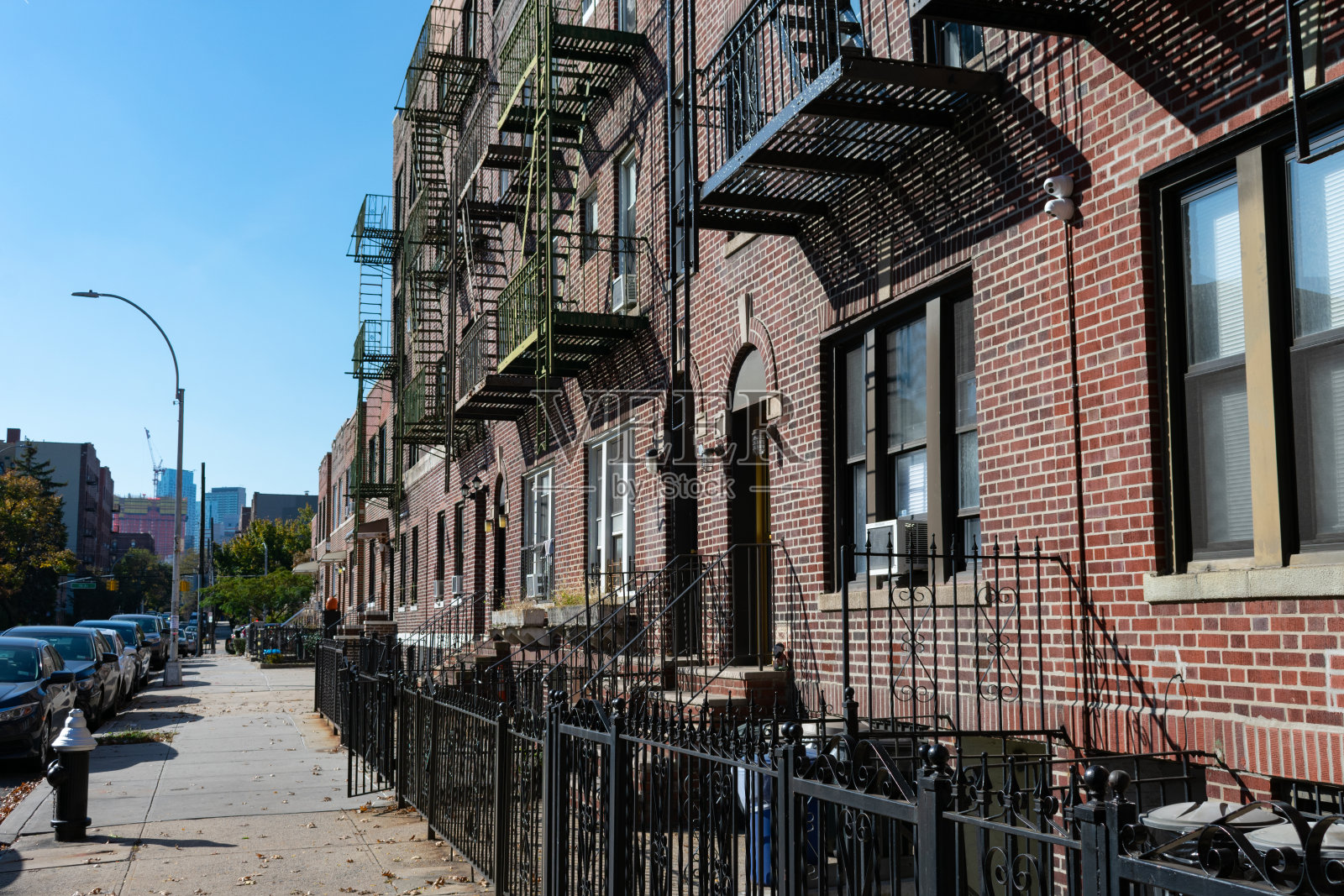 纽约皇后区阿斯托里亚的一排带有防火梯的旧砖砌住宅和人行道照片摄影图片