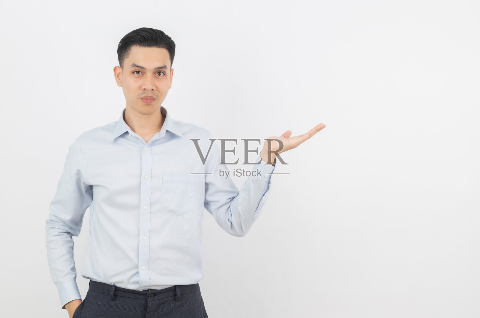 年轻的亚洲商人与蓝色衬衫指向一边与手提出一个产品或一个想法孤立在白色的背景照片摄影图片