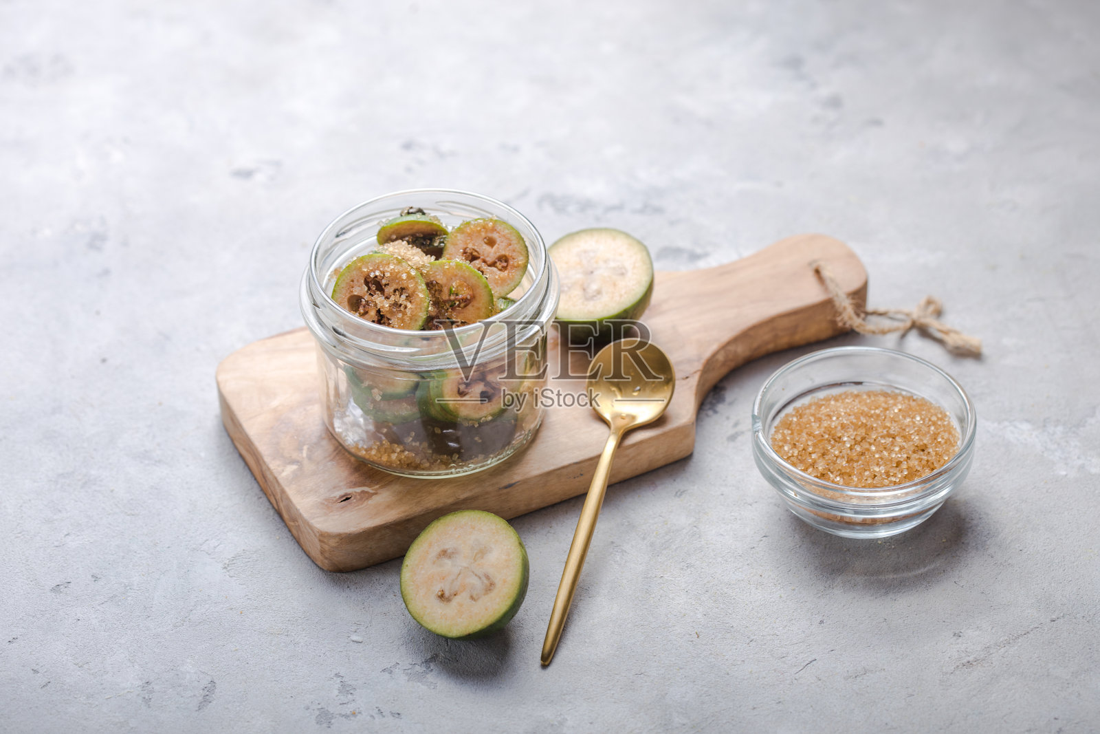 磨碎的绿feijoa加糖,放在玻璃罐中的木砧板上。灰色的背景。前视图。健康饮食成分概念照片摄影图片