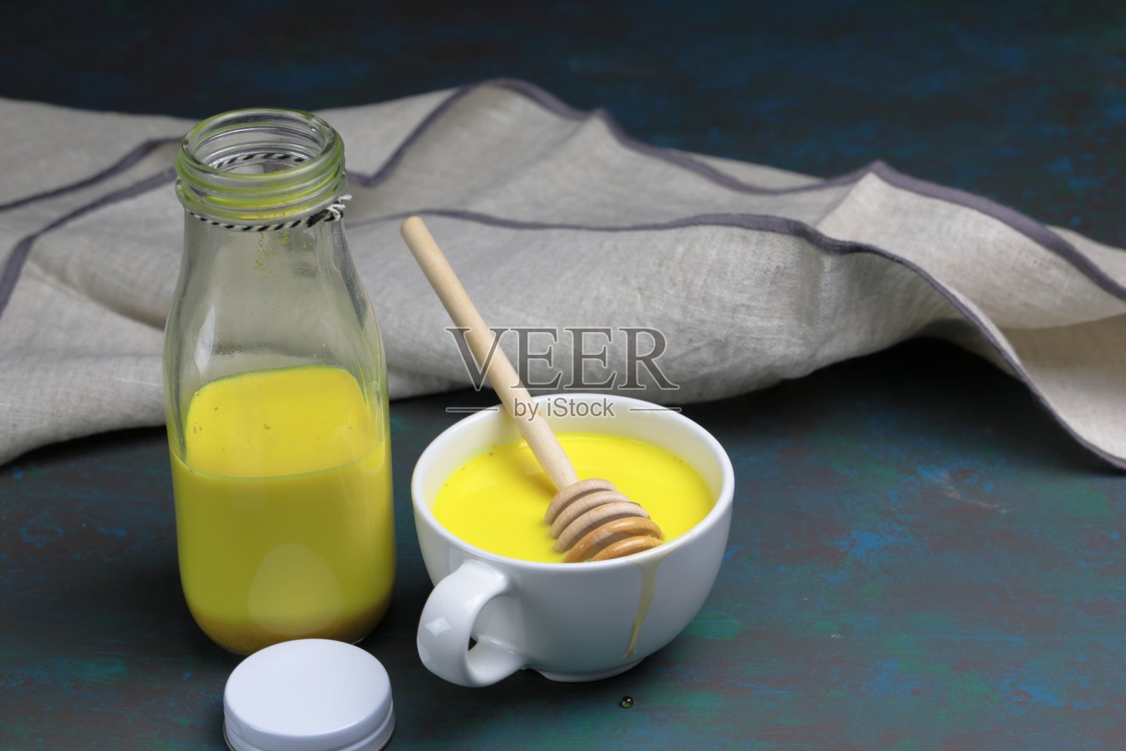 姜黄拿铁、黄金牛奶或含有超级食物姜黄粉、姜粉和肉桂的印度抗炎Doodh,在木质背景下用蜂蜜加糖照片摄影图片