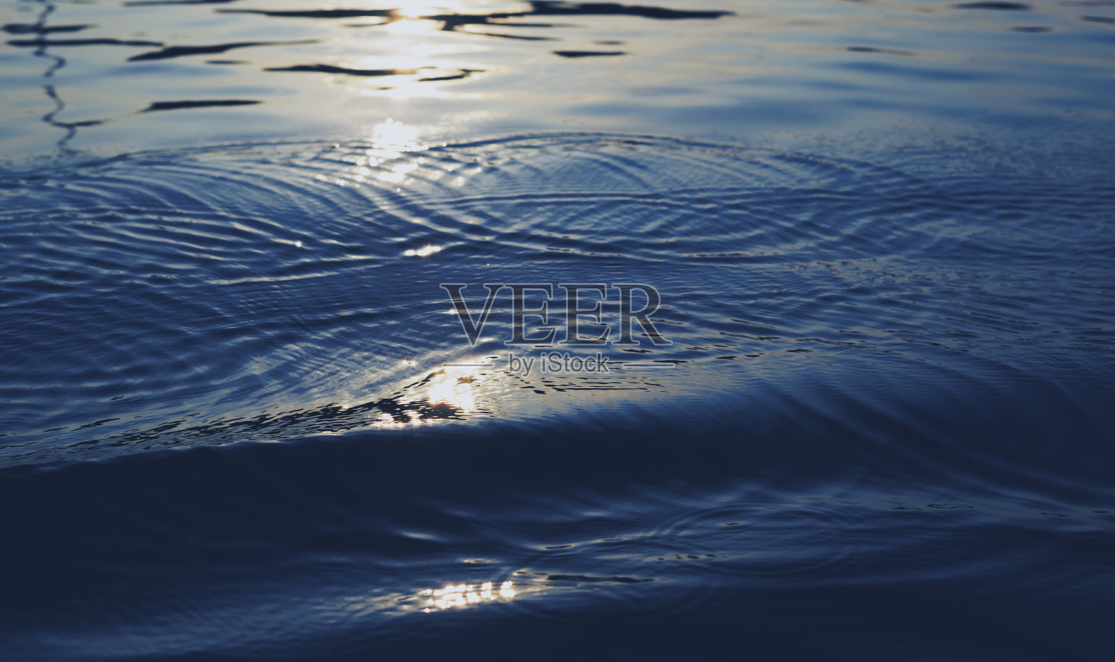 平静的湖面上泛起蓝色的波浪。照片摄影图片