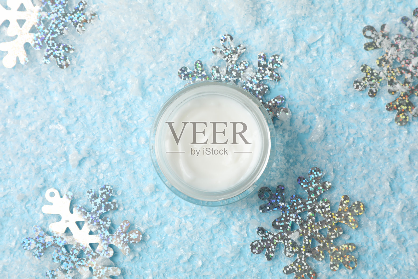 雪蓝背景,文字空间的冬季护肤霜的罐子。俯视图照片摄影图片