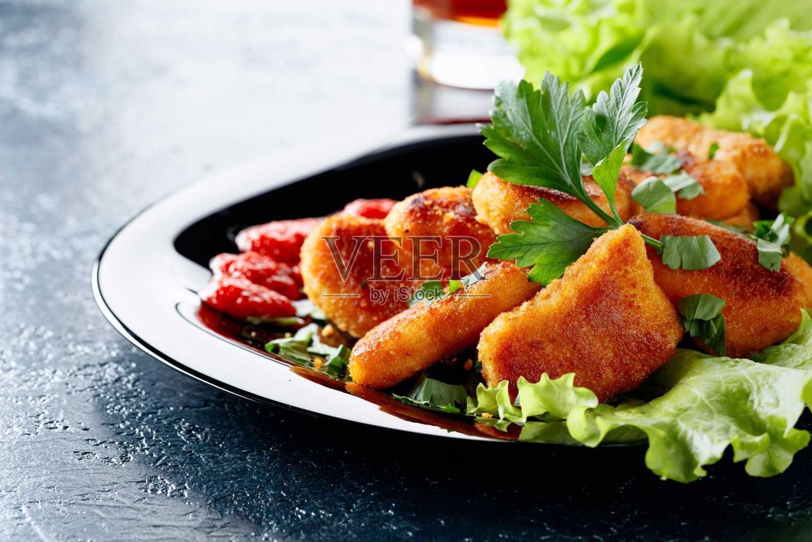 炸鸡块配番茄酱,撒上欧芹碎。照片摄影图片