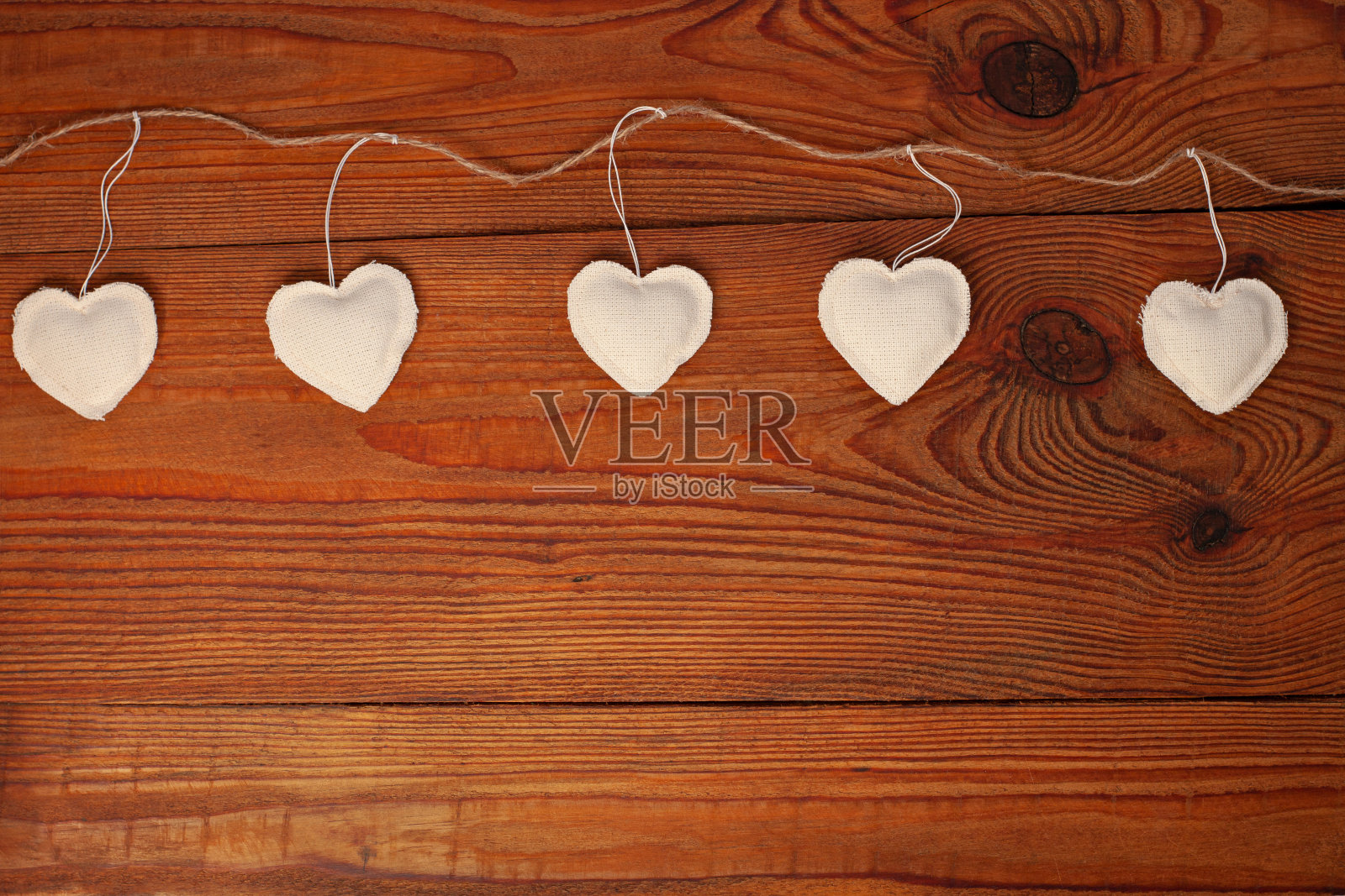 木制背景上的环保亚麻布心形,情人节概念设计。黄麻细绳花环上的装饰性白色心照片摄影图片