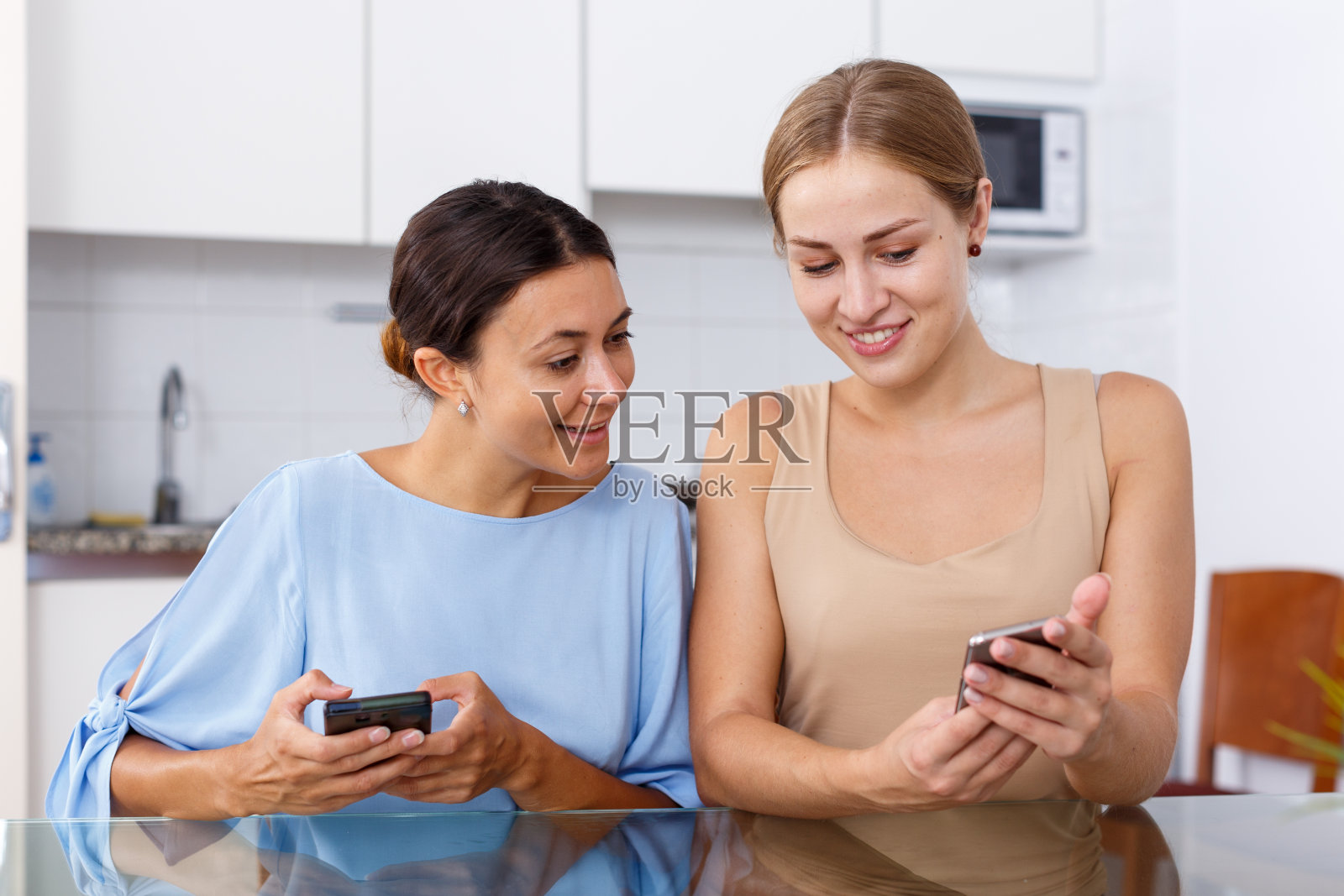 在厨房看智能手机的女孩们照片摄影图片