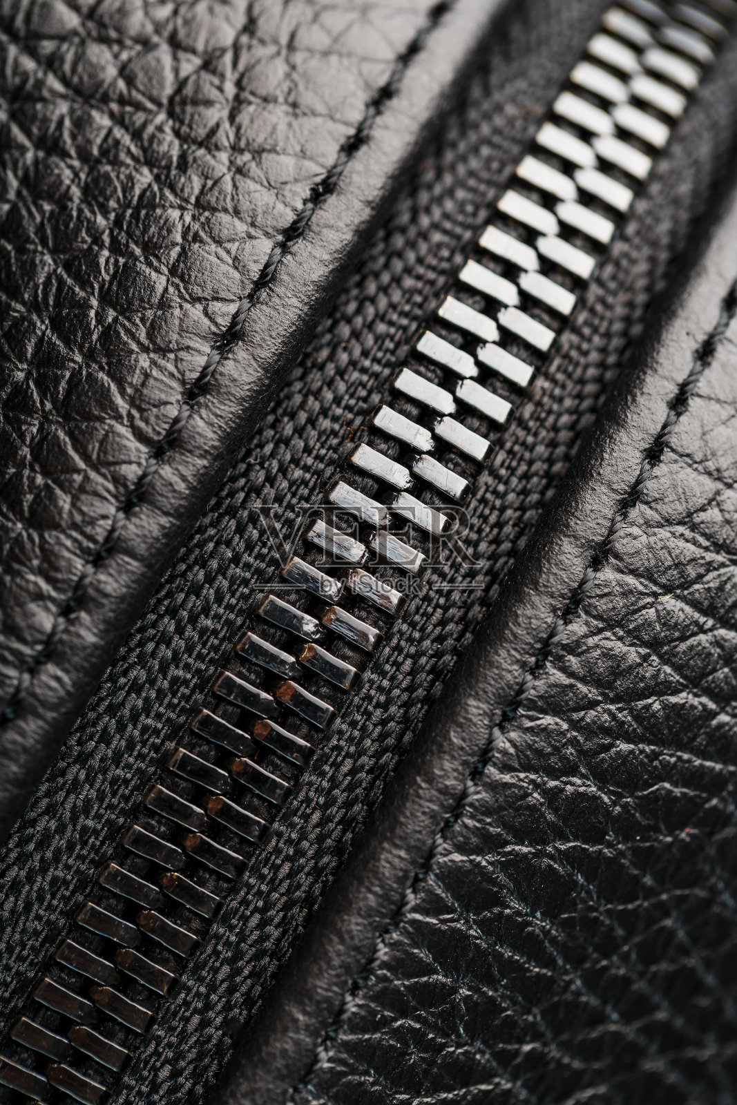 一个真正的黑色皮革包上的锁的特写,在一个黑暗的背景照片摄影图片