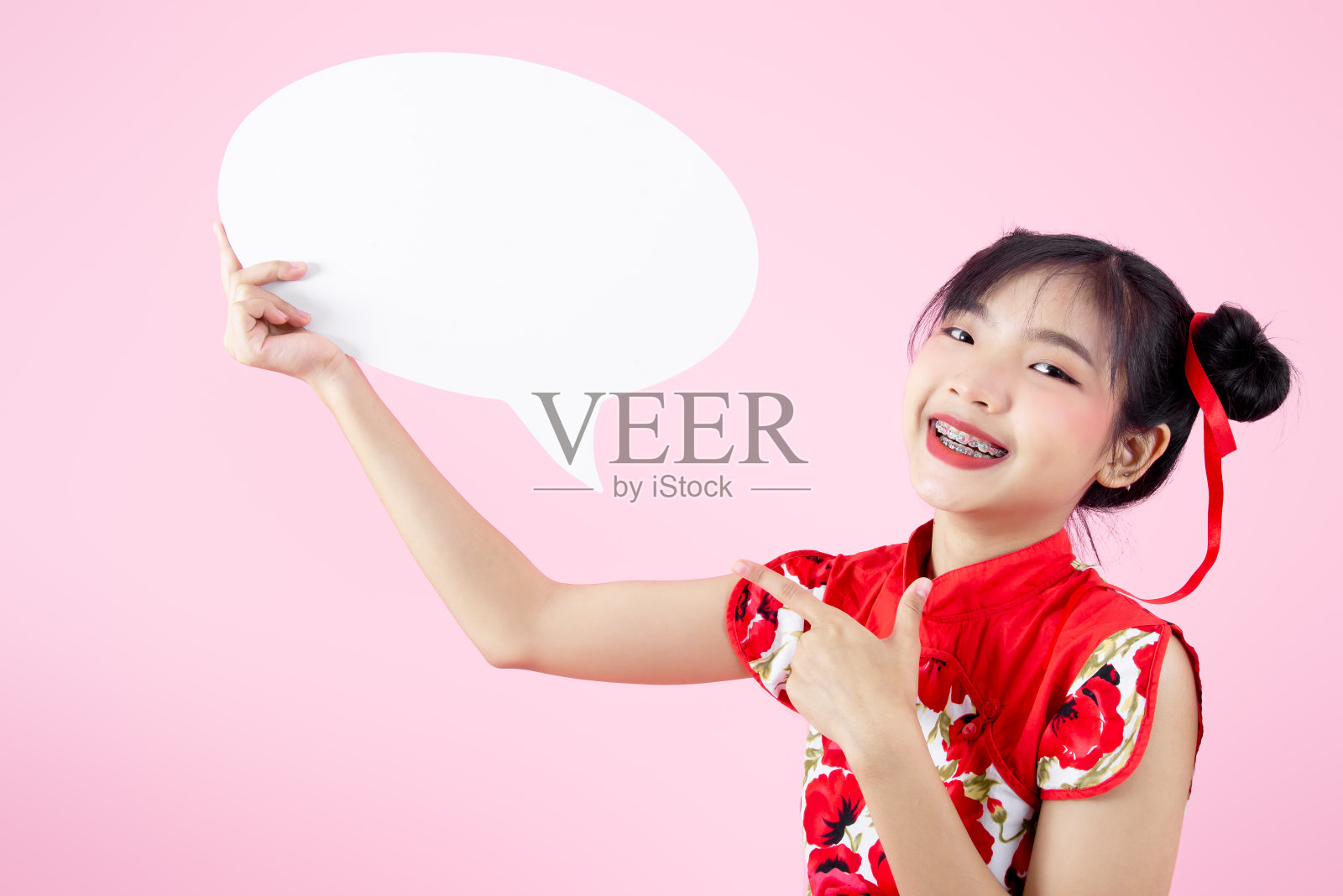 快乐的亚洲少女穿着红色旗袍,拿着粉色演讲气泡照片摄影图片