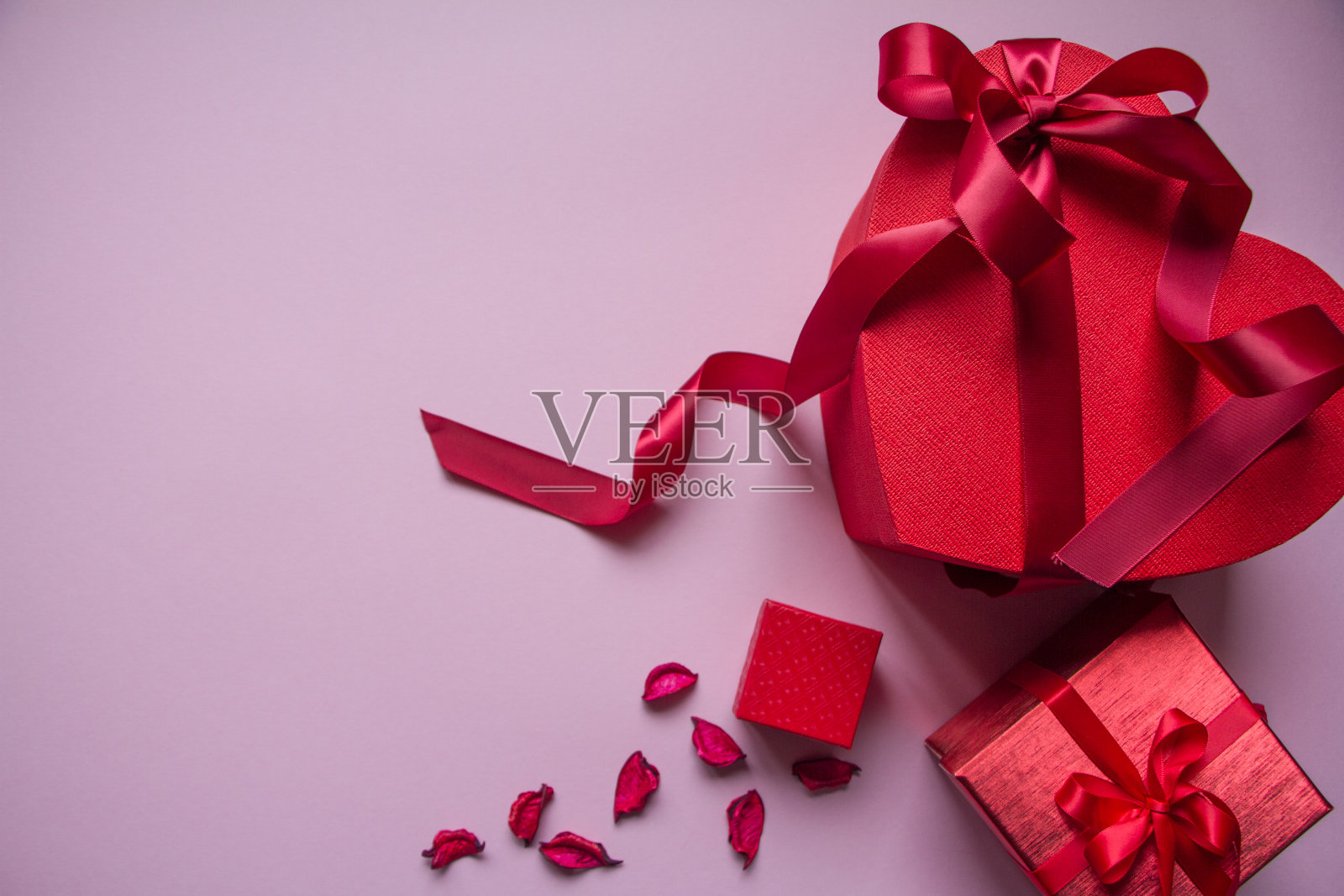 几个不同形状的红色礼品盒与红色丝带在粉红色的背景,礼物的概念照片摄影图片