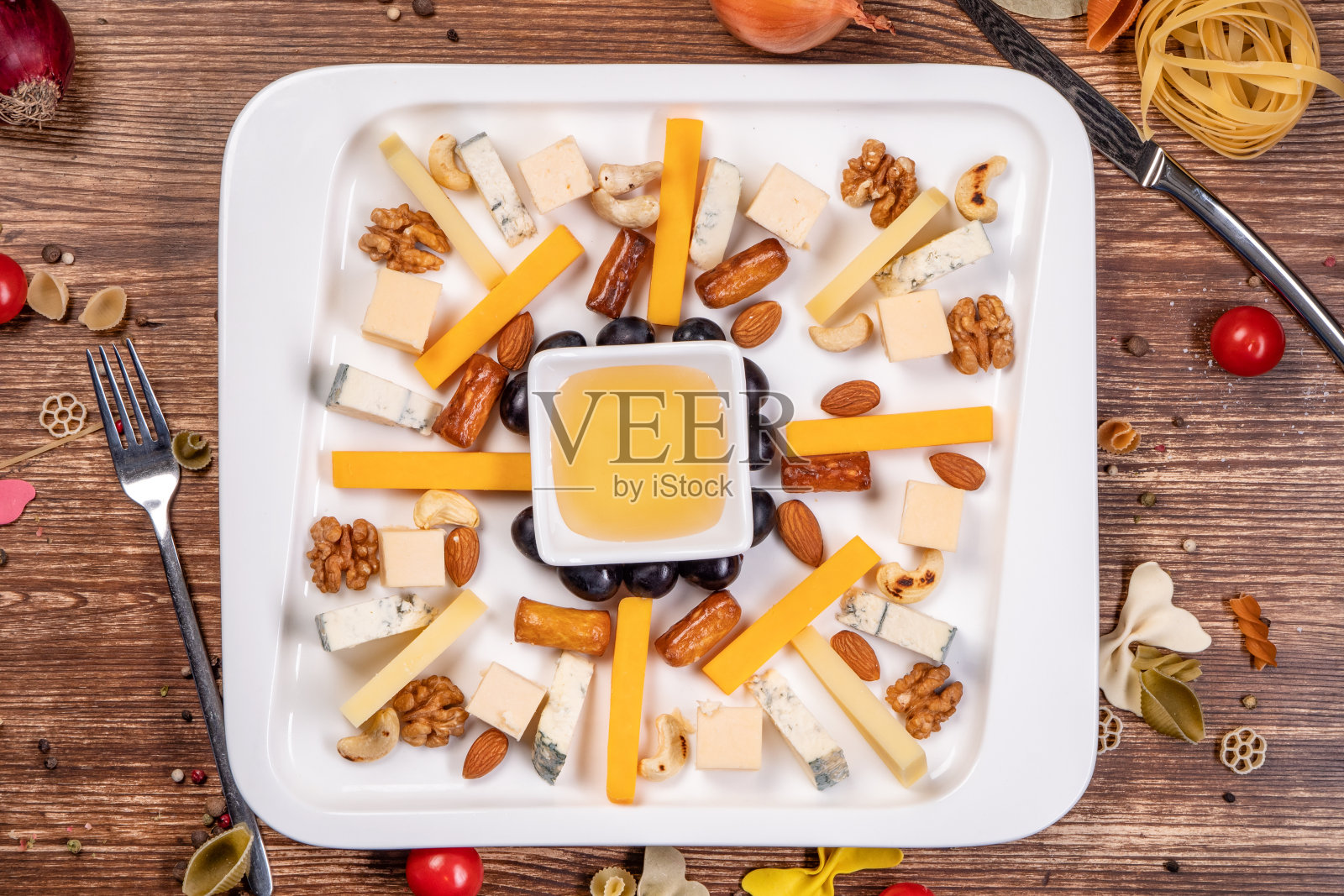 有蜂蜜和坚果的奶酪盘子。前视图。照片摄影图片