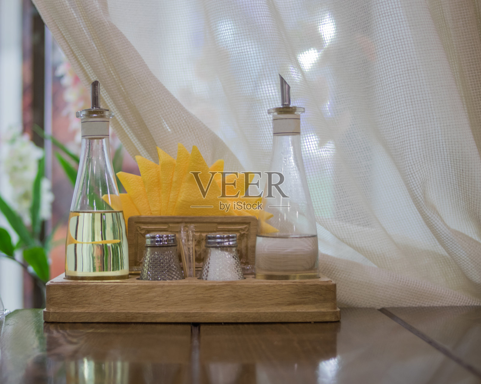 桌子上的木架子上放着盐、植物油、黑胡椒、醋和黄色纸巾等香料照片摄影图片