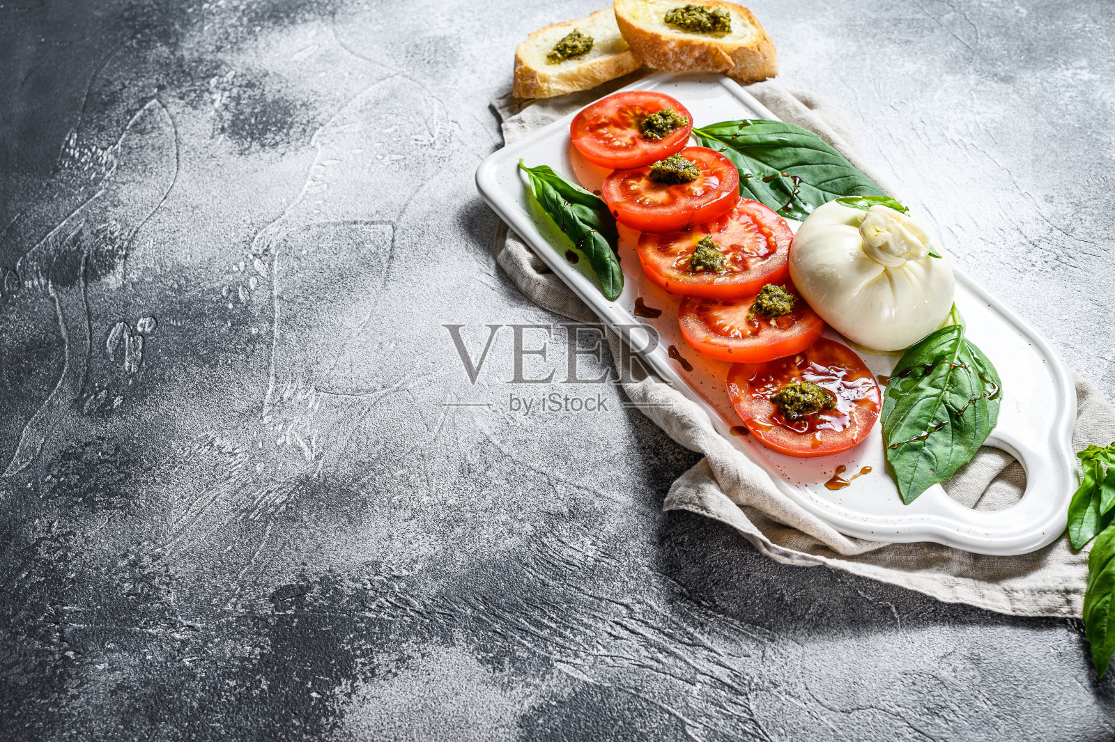 马苏里拉芝士沙拉配罗勒叶和番茄。灰色的背景。前视图。空间的文本照片摄影图片