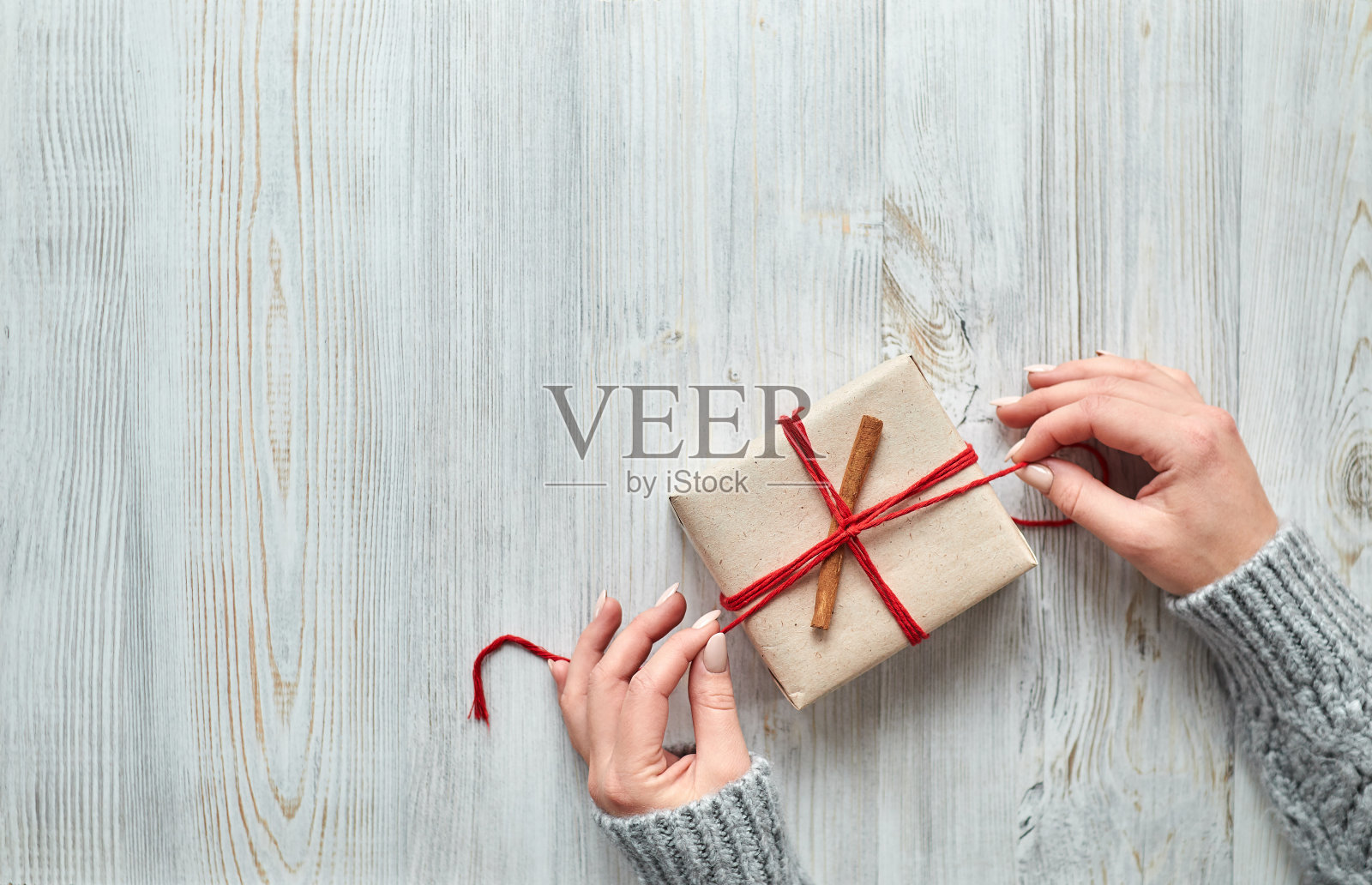 女性双手准备礼物包装在一个轻木背景照片摄影图片
