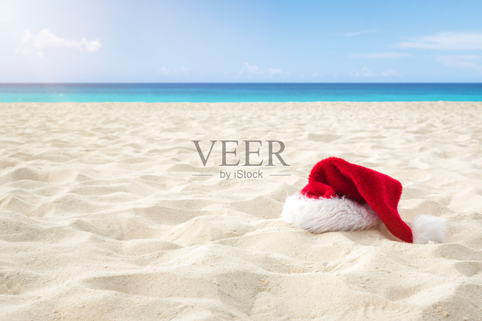 靠近圣诞老人的帽子在一个白色的沙滩无限加勒比海滩。圣诞假期旅游概念照片摄影图片