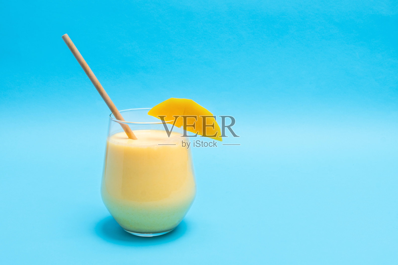 传统印度饮料芒果拉西与香料在一个玻璃杯上的蓝色背景与复制空间照片摄影图片