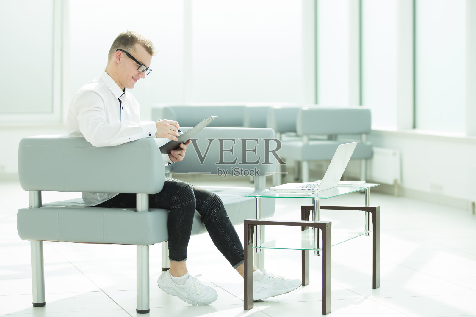 一个商人坐在办公室的大厅里看商务文件照片摄影图片