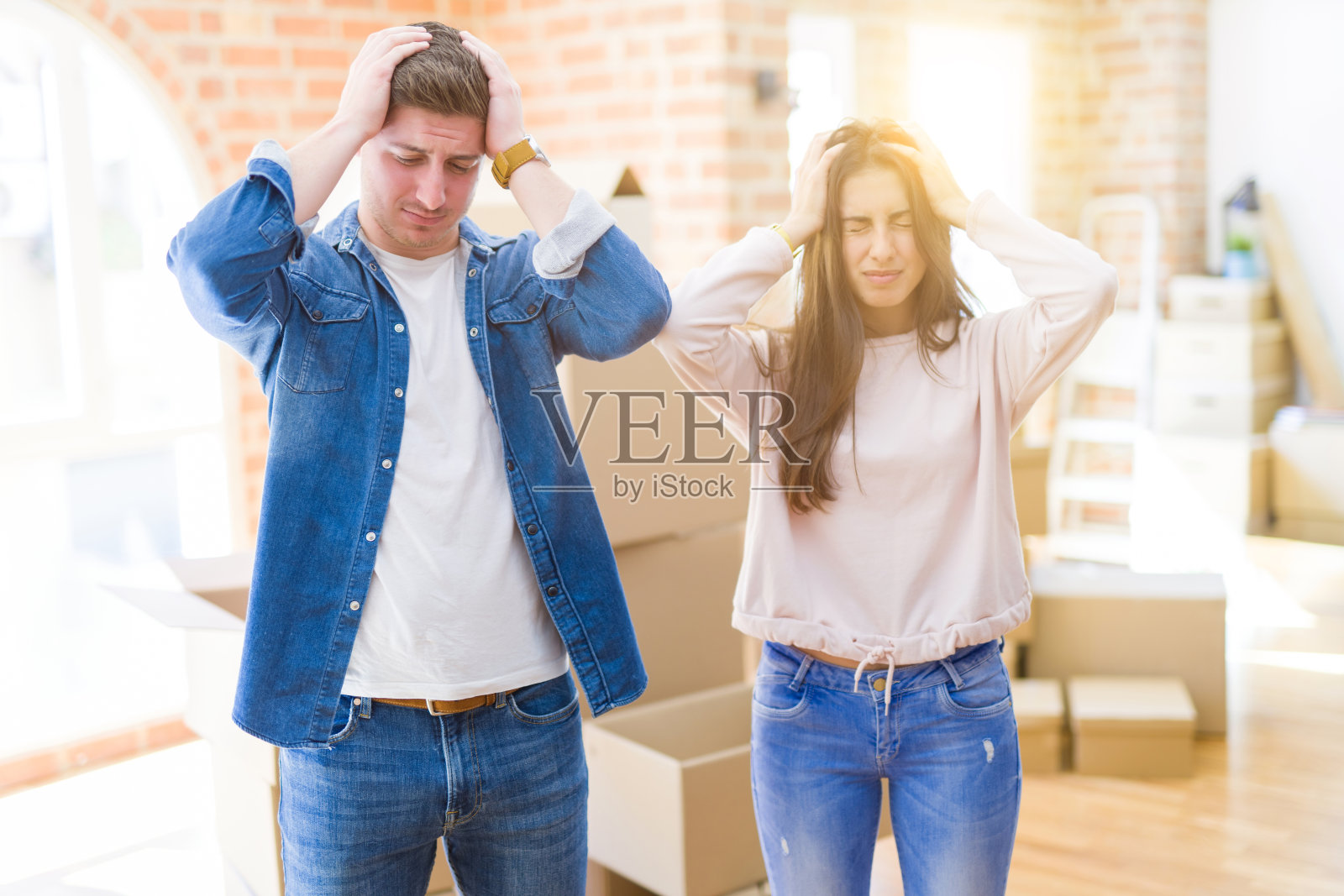 年轻情侣搬进新家,头痛欲裂,感到绝望和压力照片摄影图片