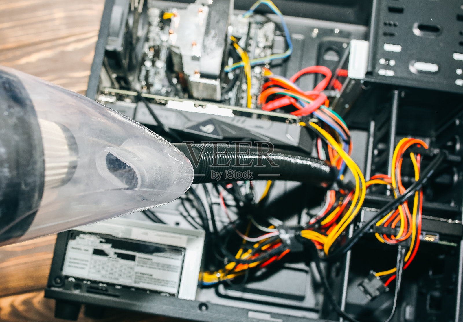 个人电脑的内部细节。人类正在用吸尘器清扫电线。小胡佛。主板和显卡在灰尘中。破电脑。照片摄影图片