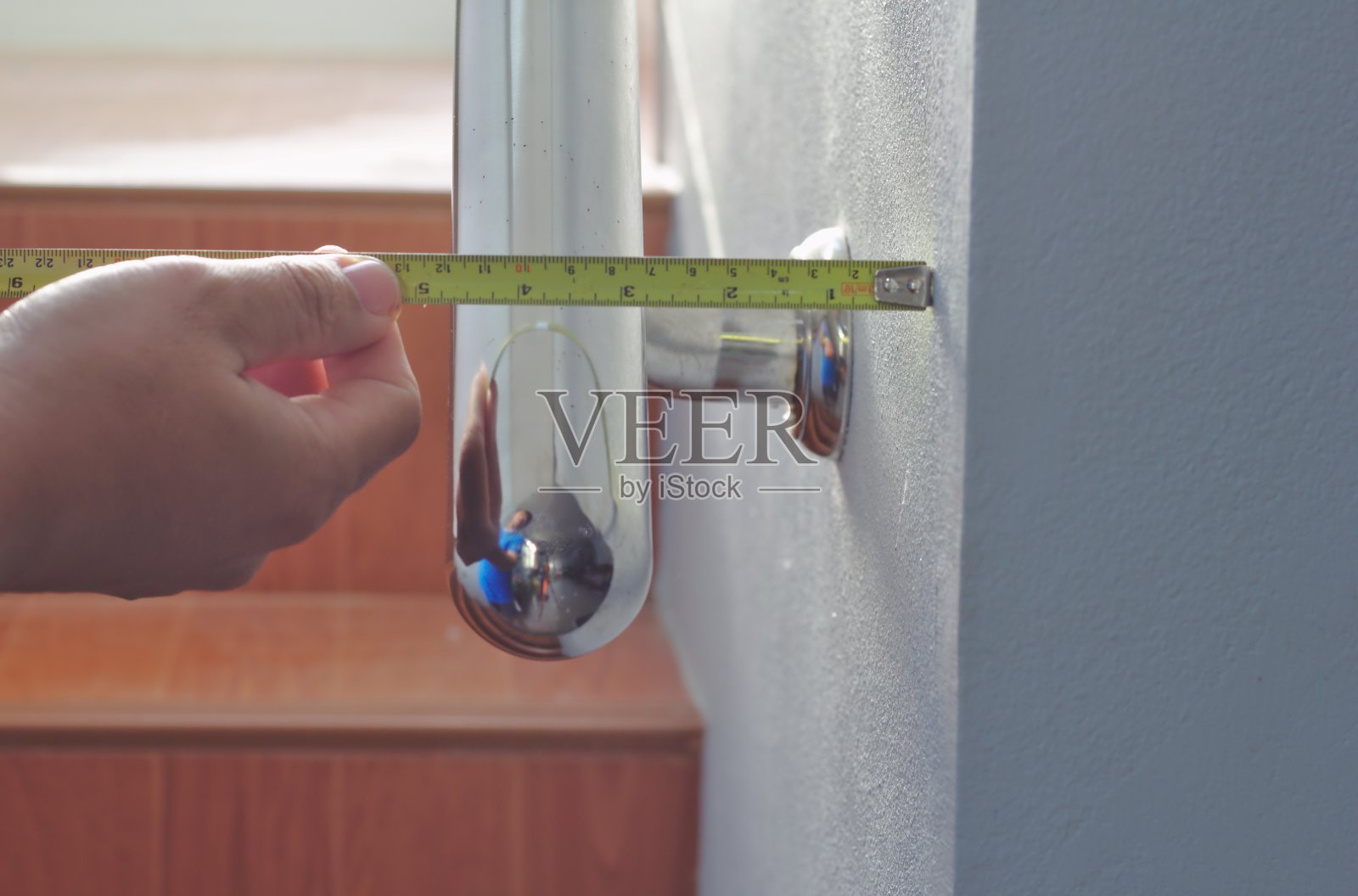 金属卷尺测量墙壁。安装栏杆。办公大楼的不锈钢扶手和白色楼梯照片摄影图片