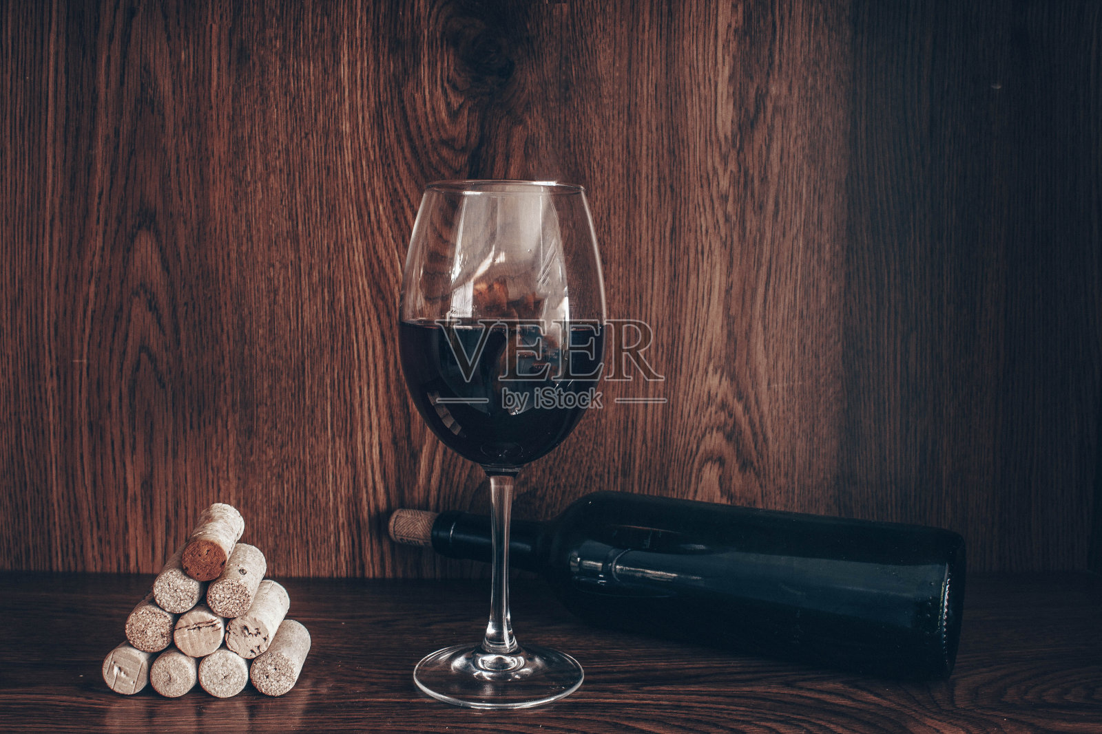 木背景上的软木塞、红酒杯和红酒瓶的照片照片摄影图片