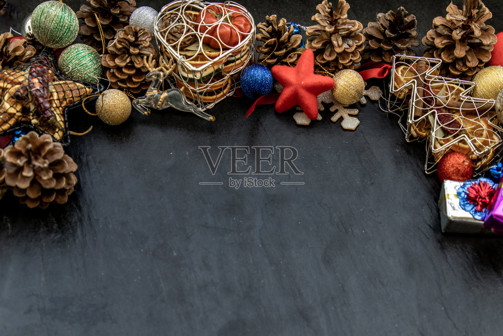 宽大的拱形圣诞装饰边框。树枝圣诞树,棕色的天然松果和和圣诞鹿与各种水果在黑暗的背景。照片摄影图片