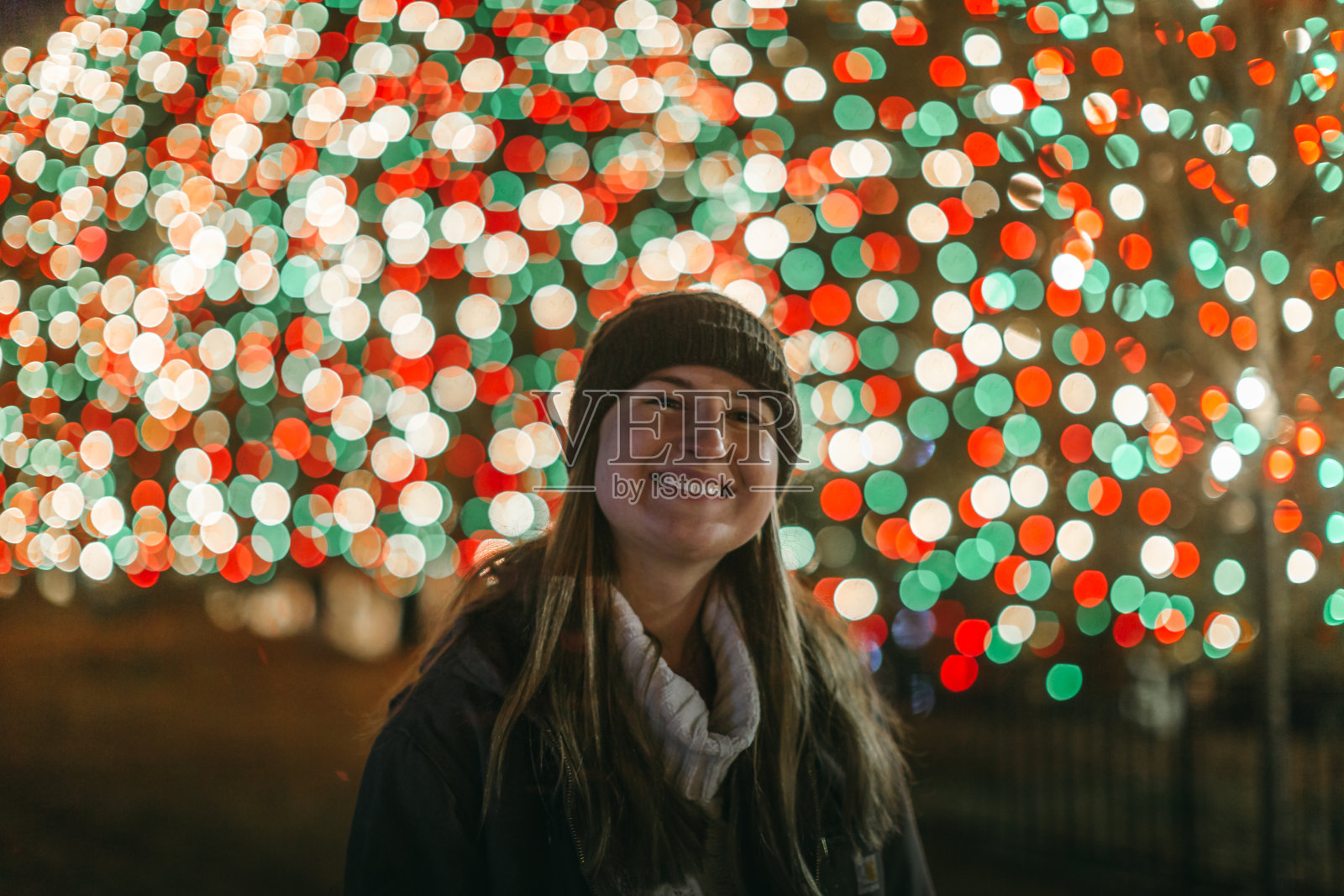 带着圣诞彩灯微笑的年轻女子照片摄影图片