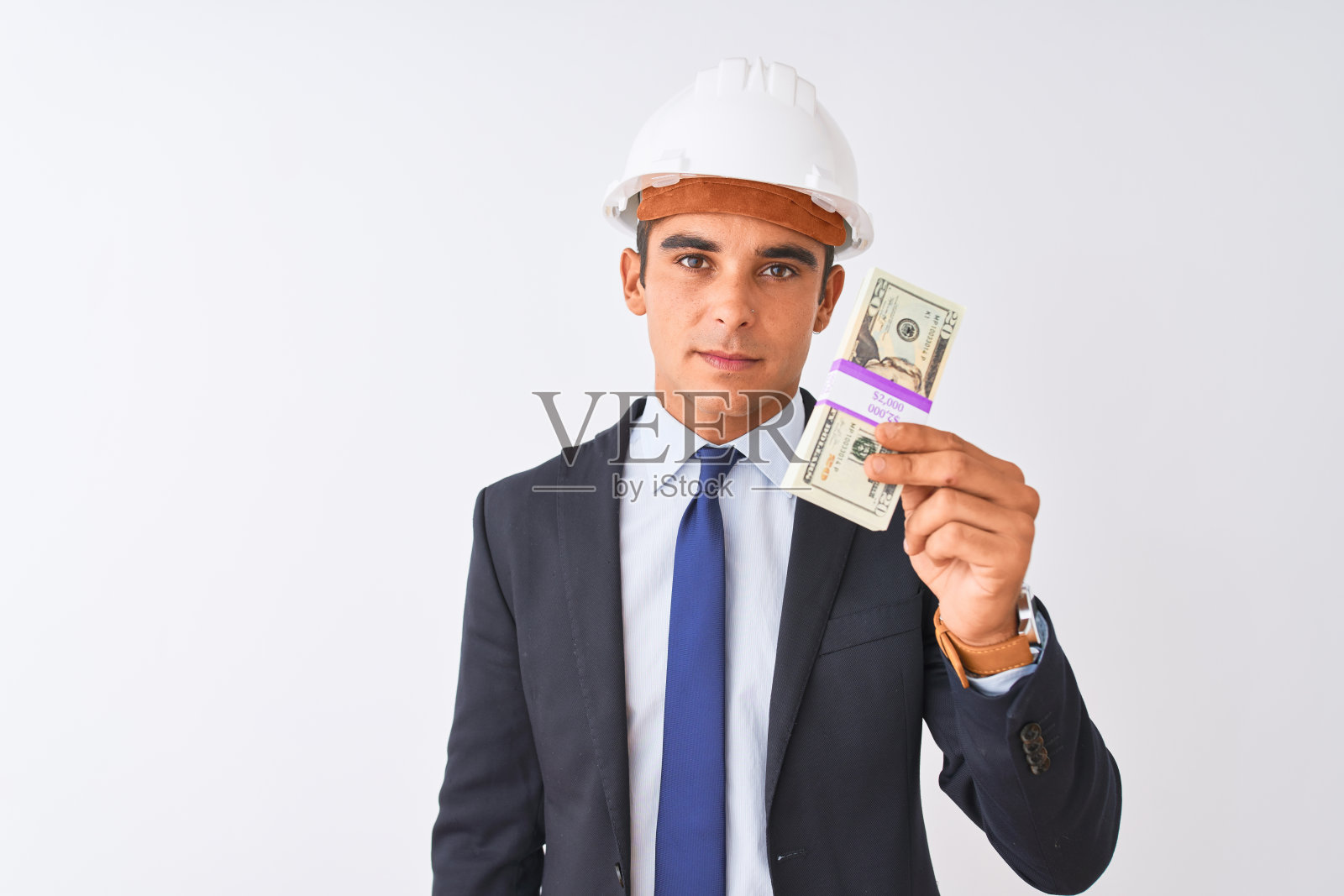 年轻英俊的建筑师男子戴着头盔,手持美元越过孤立的白色背景与自信的表情在聪明的脸上思考严肃照片摄影图片