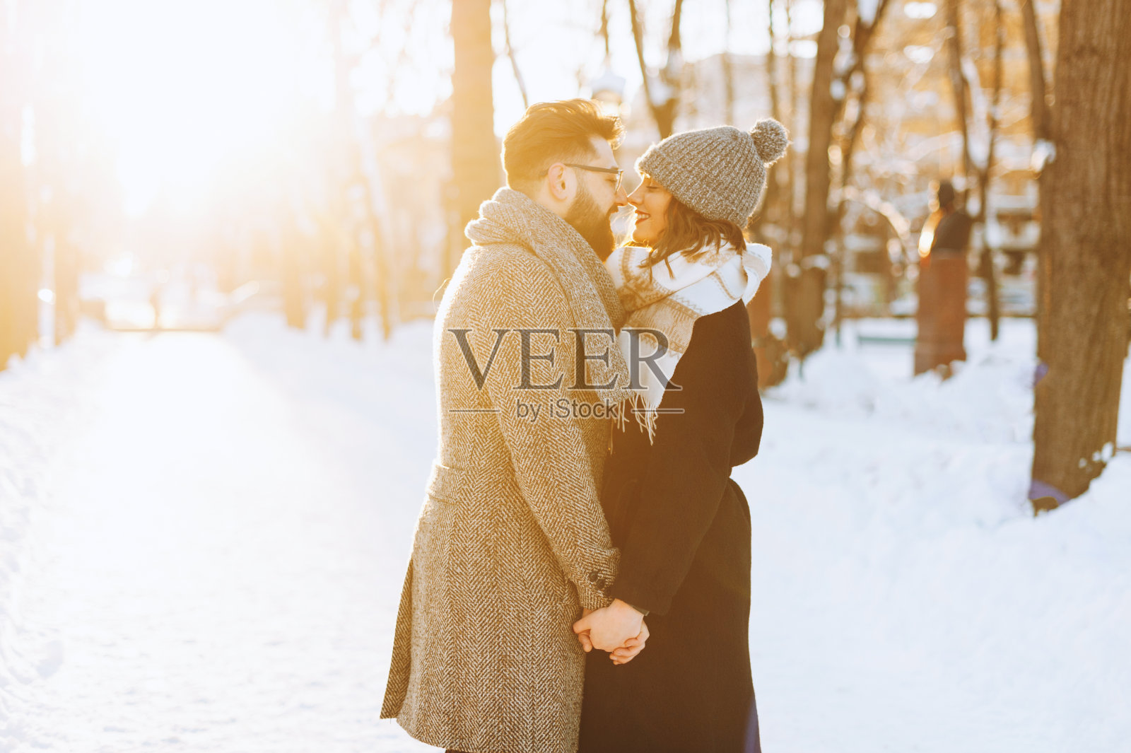 年轻幸福的夫妇看着对方,享受他们的时间在公园在冬天。照片摄影图片