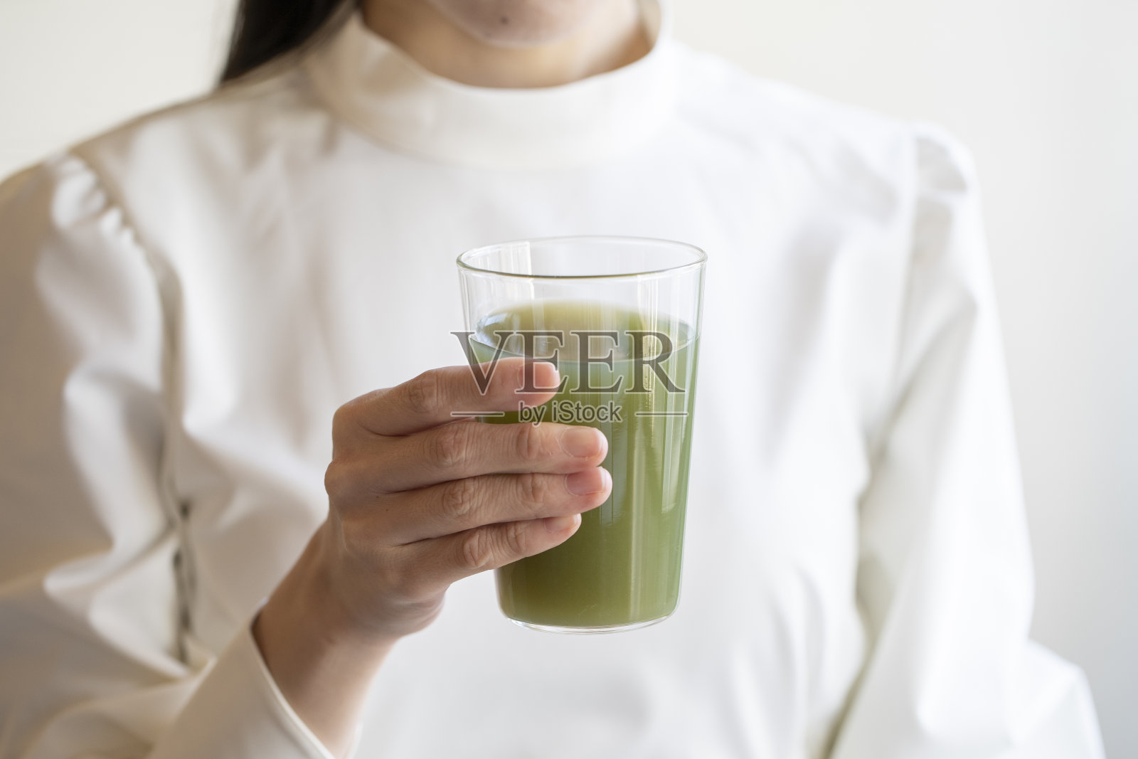 年轻女子用手将绿汁倒进玻璃杯照片摄影图片