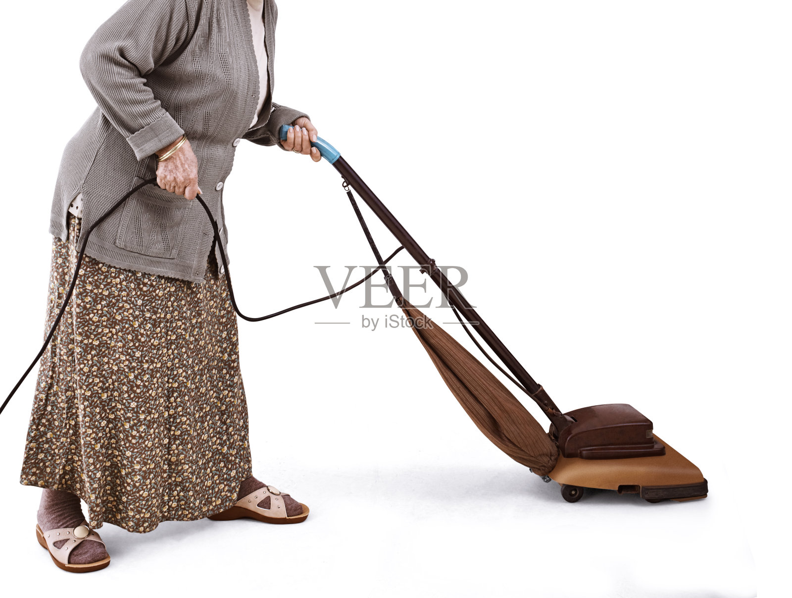 老妇人在用老式吸尘器。照片摄影图片