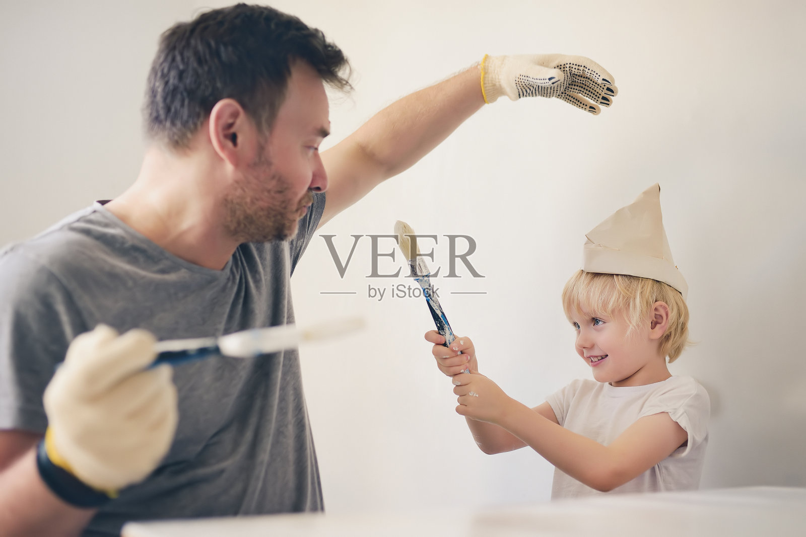 成熟的男人和小男孩在一起玩油漆刷修复房间。照片摄影图片