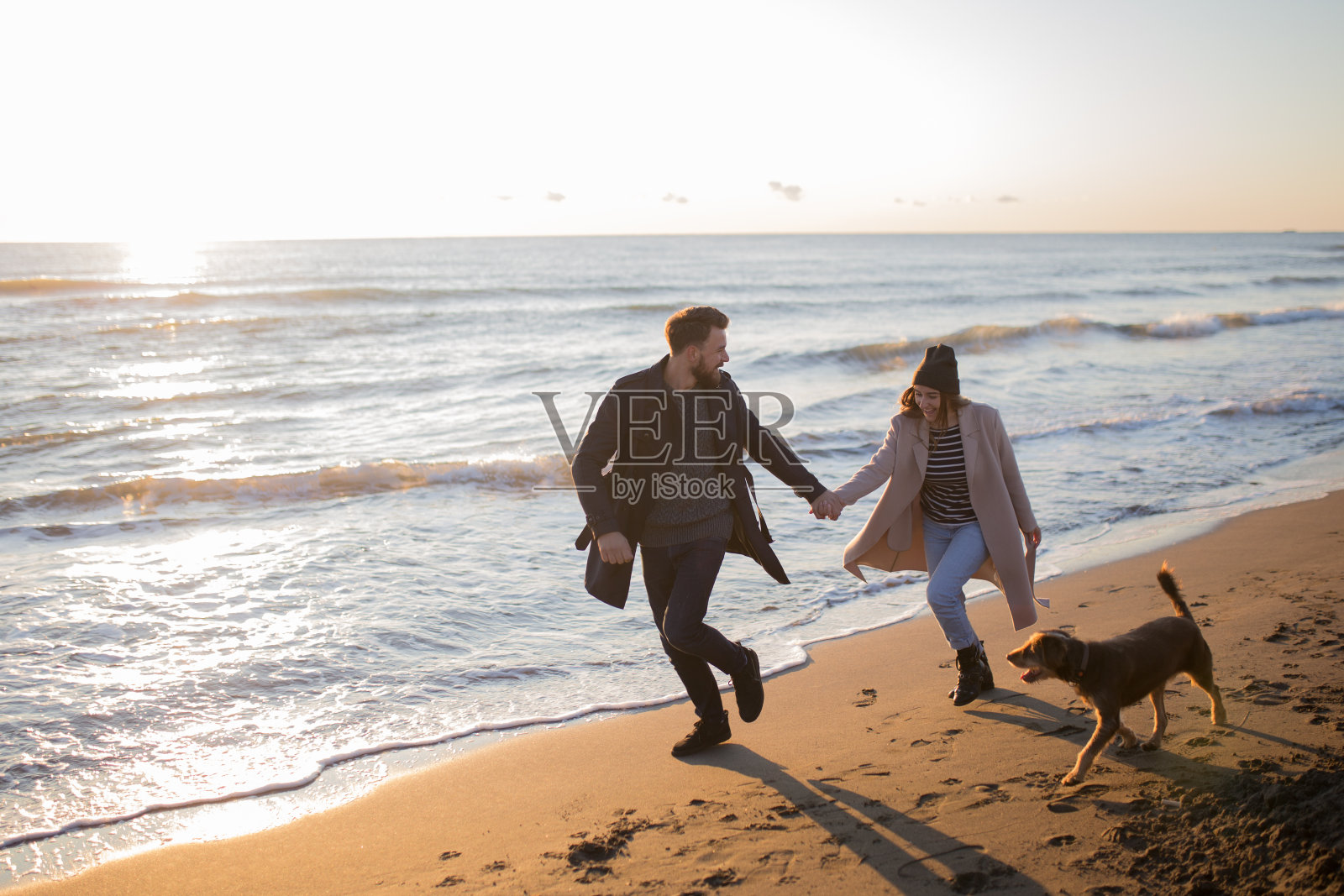 新婚夫妇带爱犬在海滩享受蜜月时光照片摄影图片