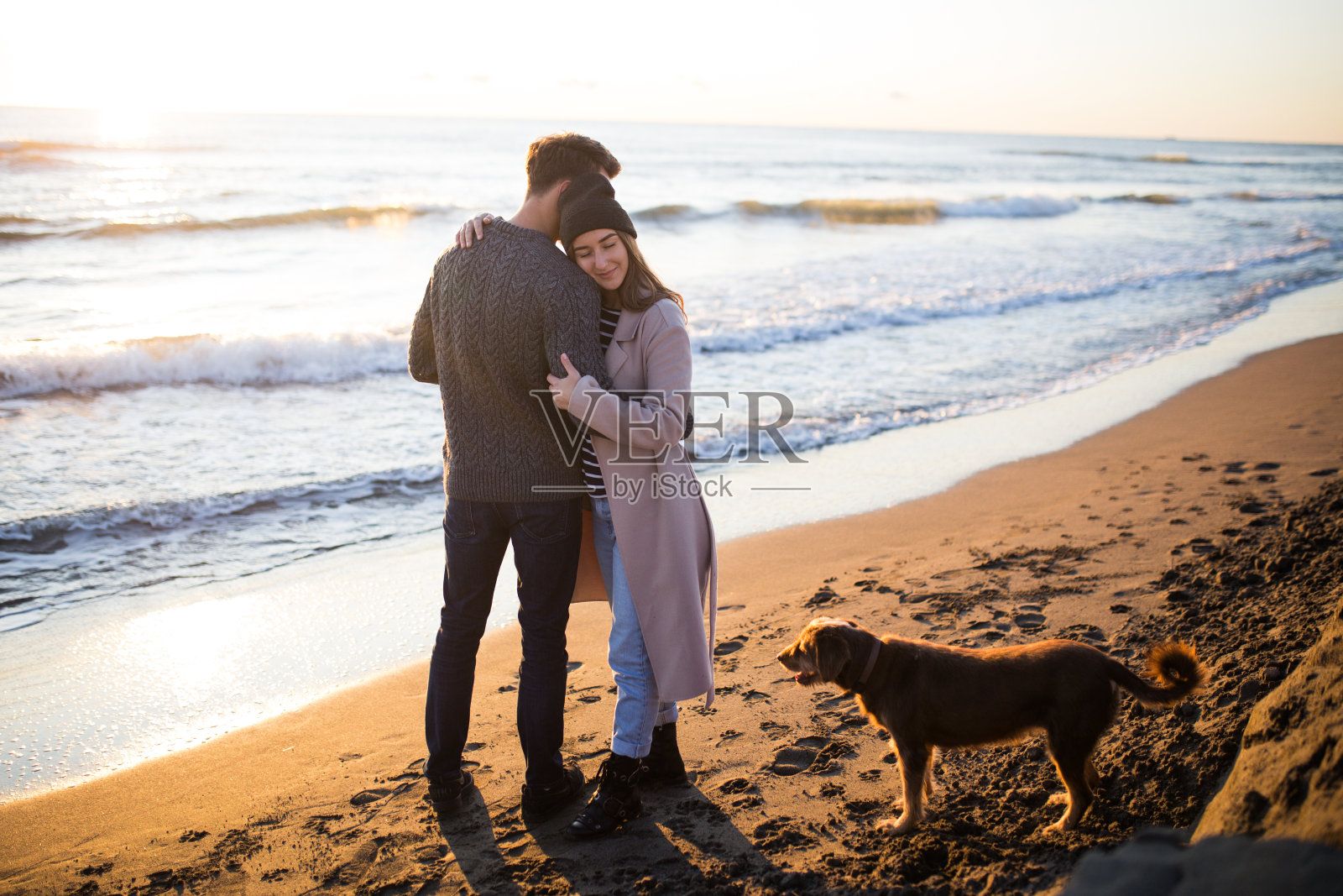 年轻的小轿车拥抱在海滩在冬天的时间在日落前。照片摄影图片