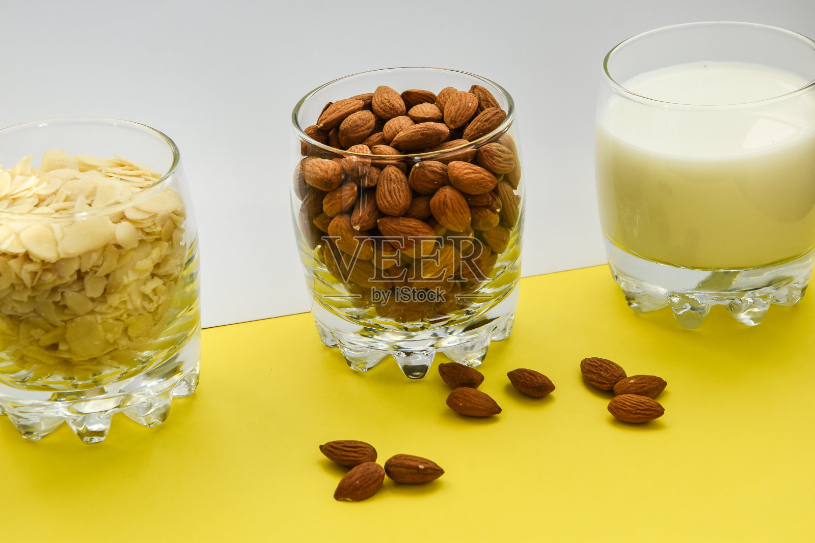 杯子里有杏仁,还有杏仁片和杏仁牛奶,背景是白色和黄色照片摄影图片