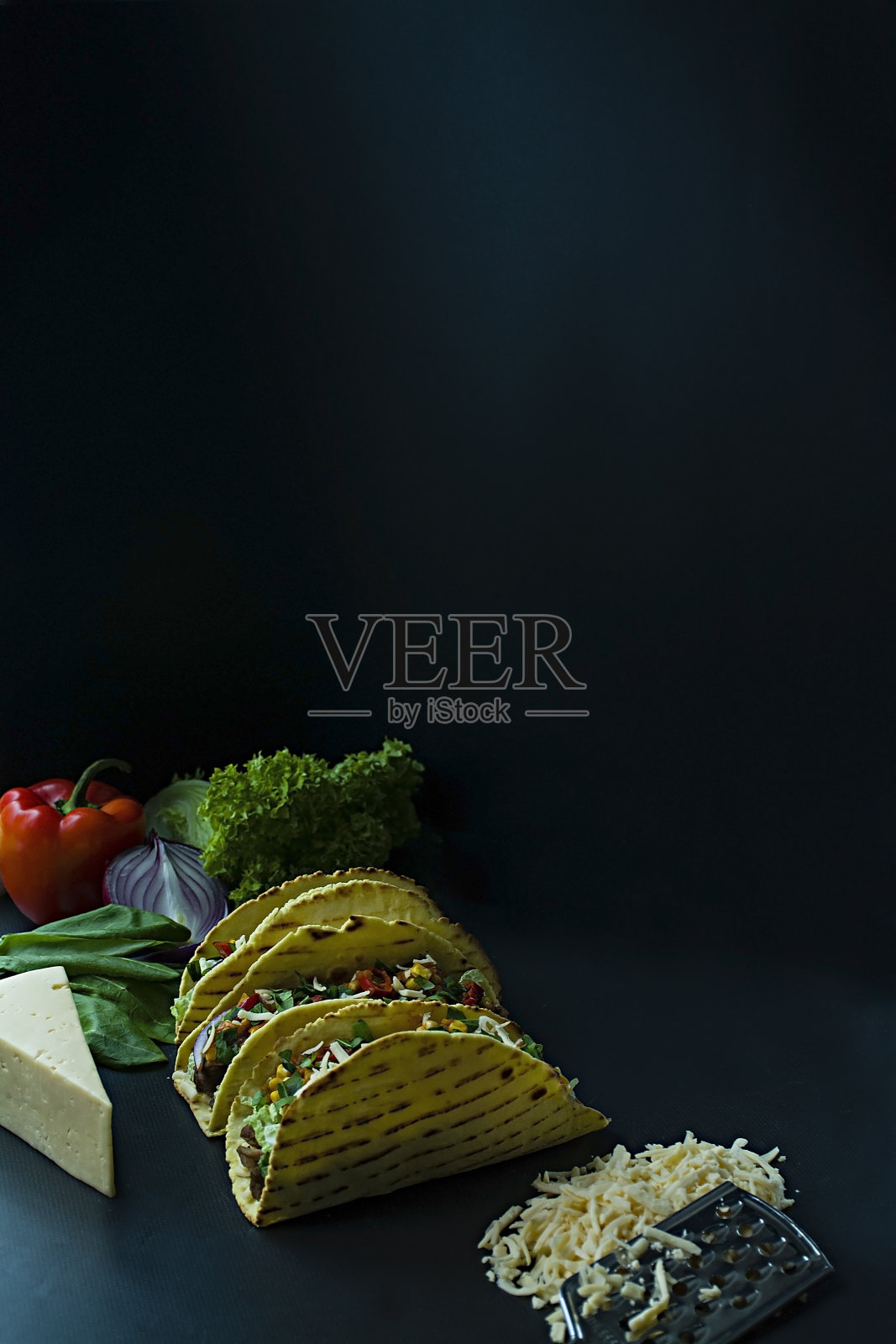 墨西哥玉米饼,猪肉,奶酪,玉米,洋葱和香草放在木板上的照片。加番茄酱和辣椒。黑色背景。侧视图。照片摄影图片