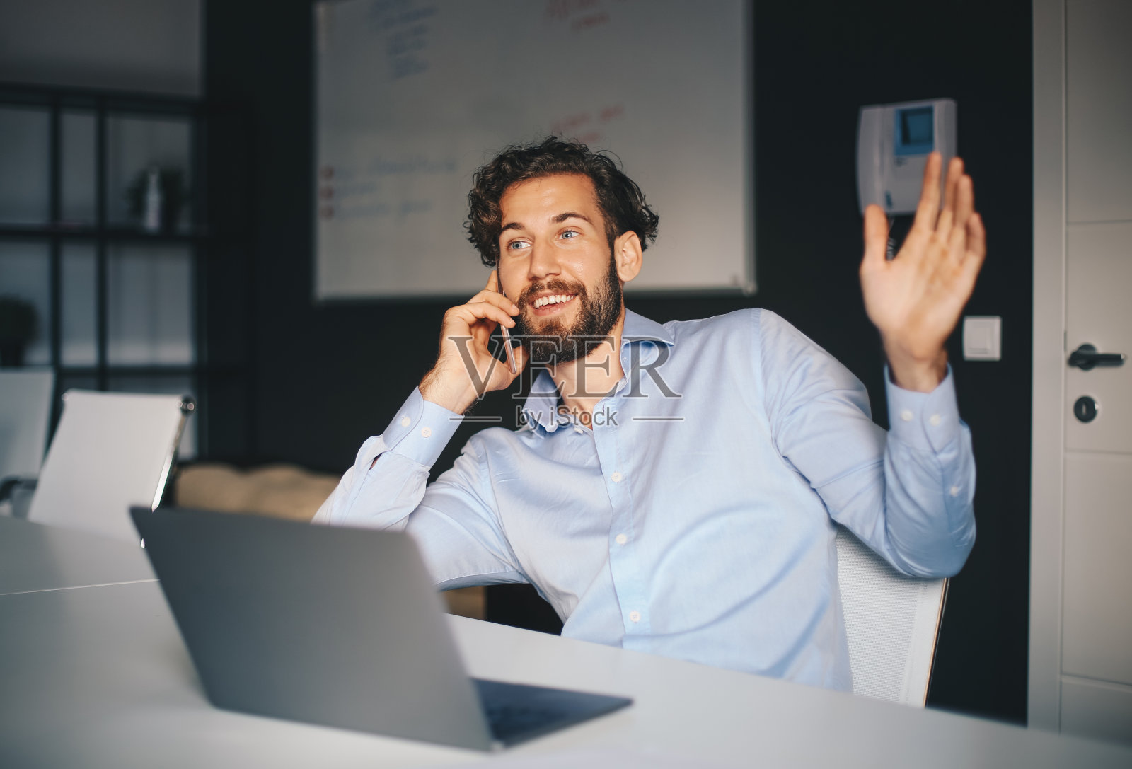 一个商人在他的办公室里打电话。照片摄影图片