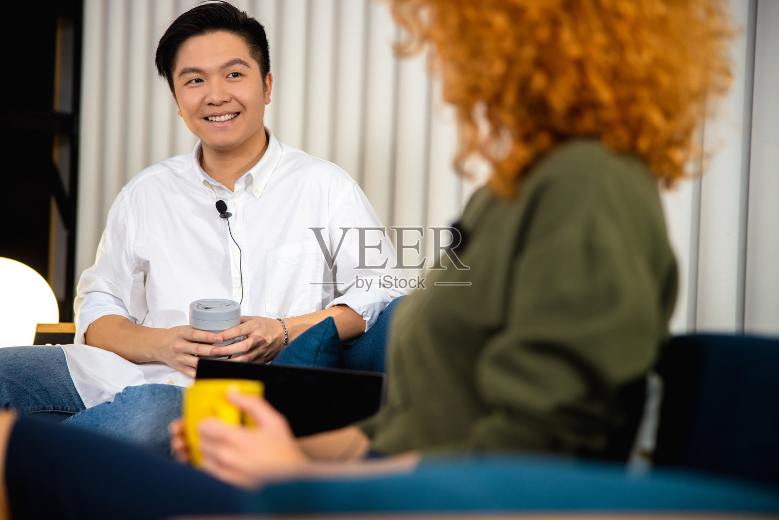 快乐的年轻人拿着热饮料,而与女士交谈照片摄影图片