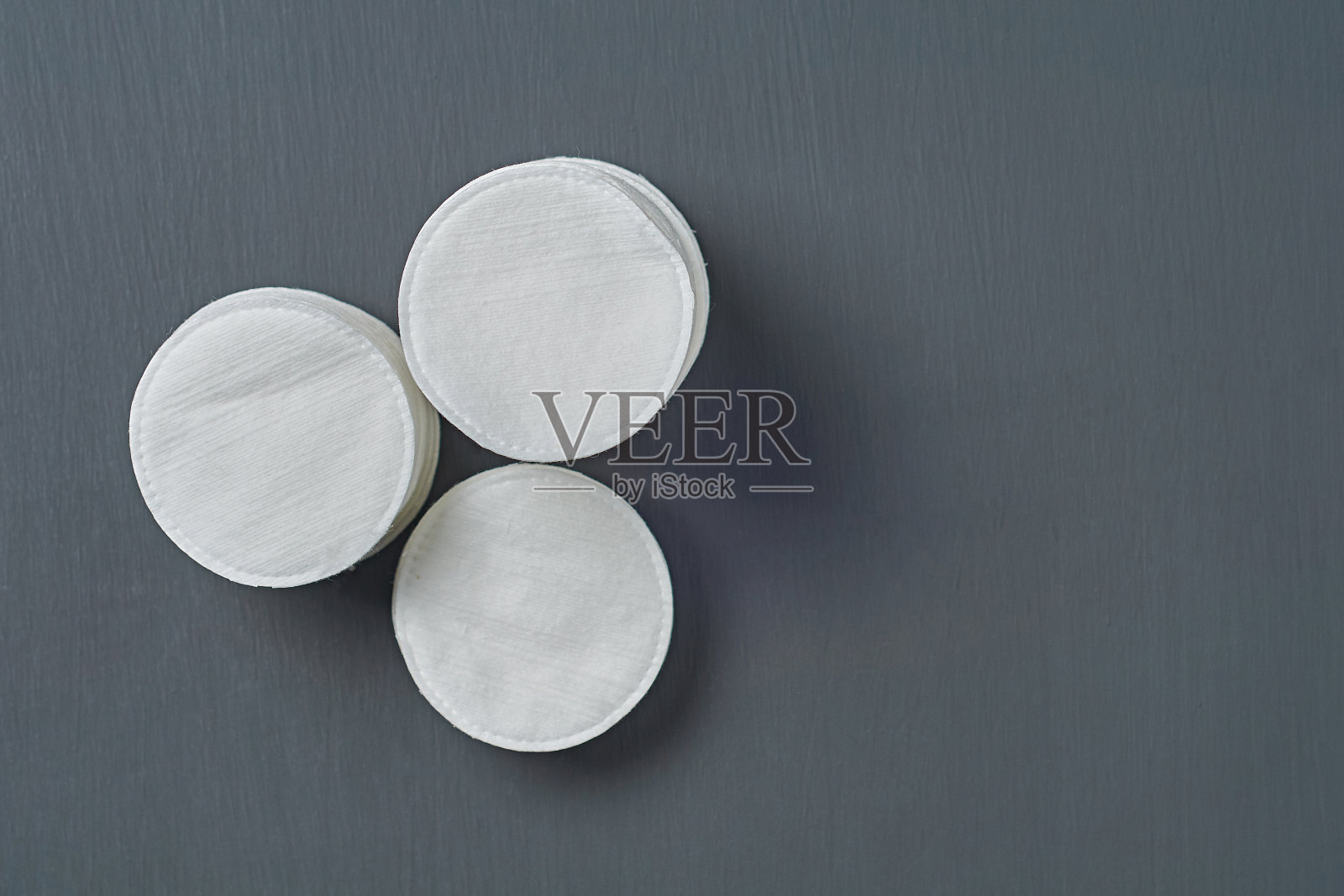 黑色的混凝土桌子上放着一堆卫生用的圆形棉垫。空间的文本。俯视图照片摄影图片