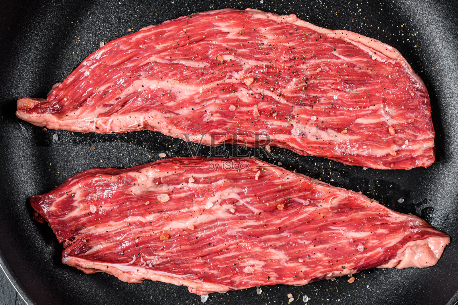 煎锅里的生牛排。黑色背景。俯视图照片摄影图片