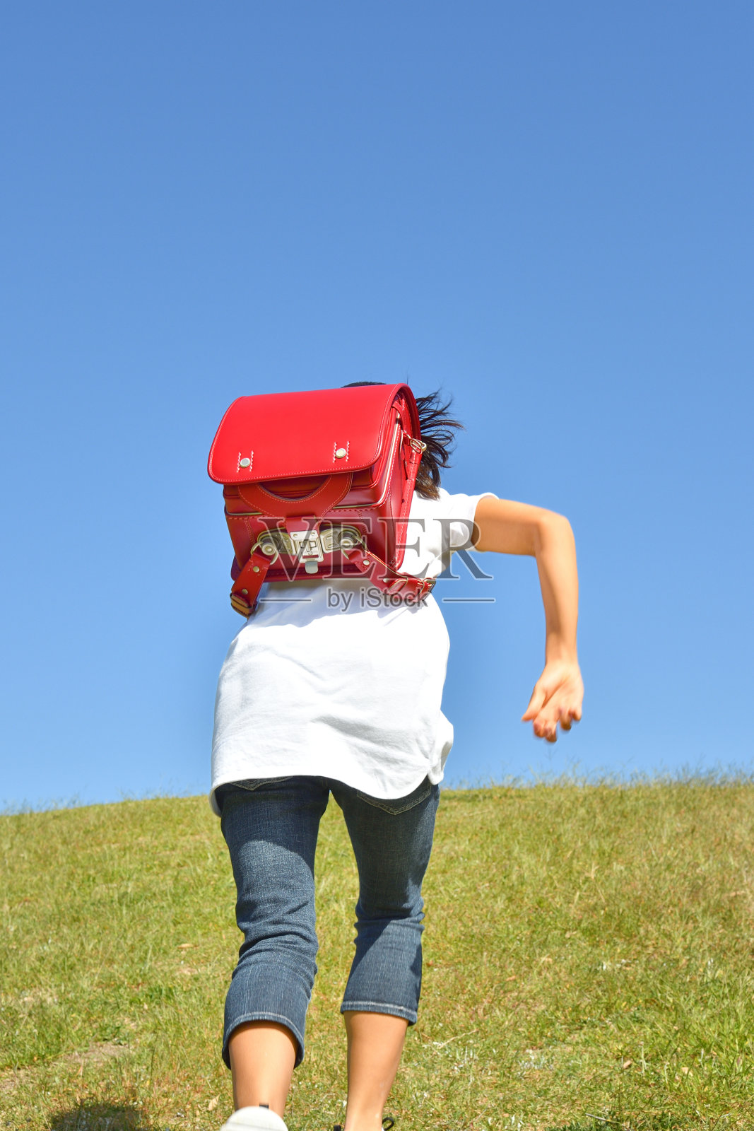 日本小学女孩在蓝天中奔跑-后视图照片摄影图片