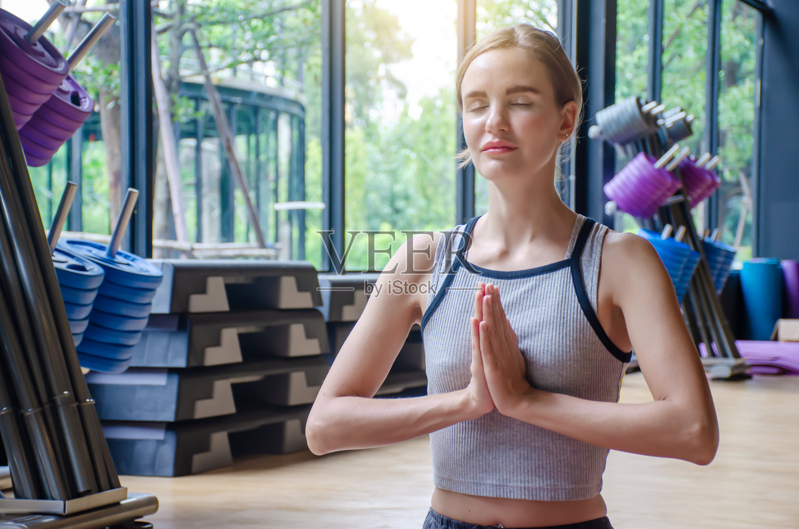 年轻迷人的女人练习瑜伽闭上眼睛放松,坐在莲花坐练习瑜伽,迷人的运动女孩穿着灰色运动服在家里或瑜伽工作室工作照片摄影图片